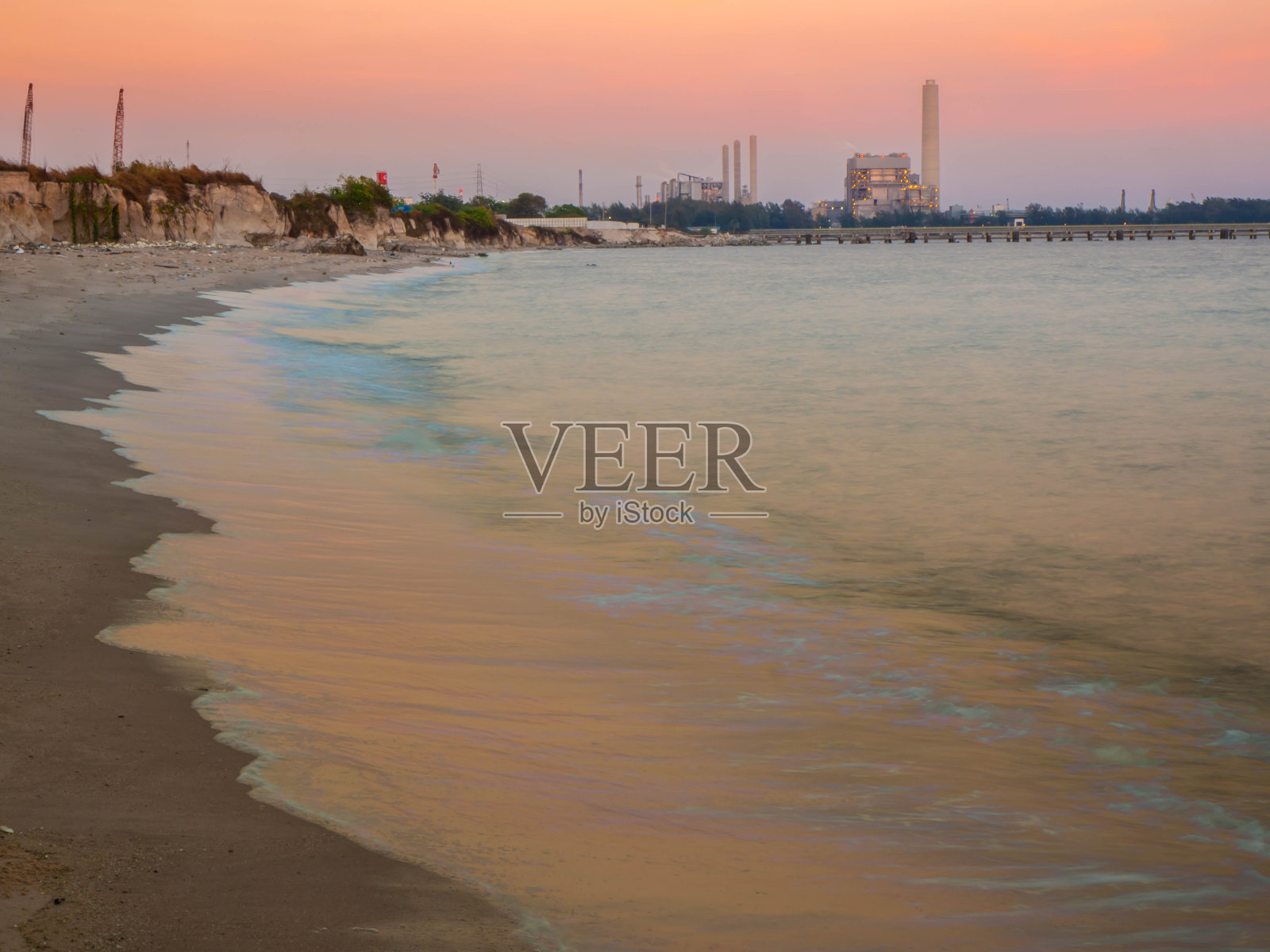 石油和天然气精炼工业工厂日落在海岸。照片摄影图片