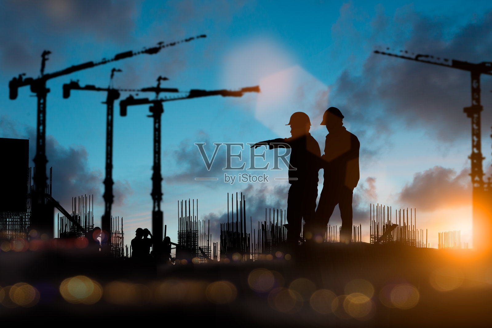工程师和施工队在现场工作的剪影在模糊的背景与光博览会和散景工业背景。从多个参考图像一起创建。照片摄影图片
