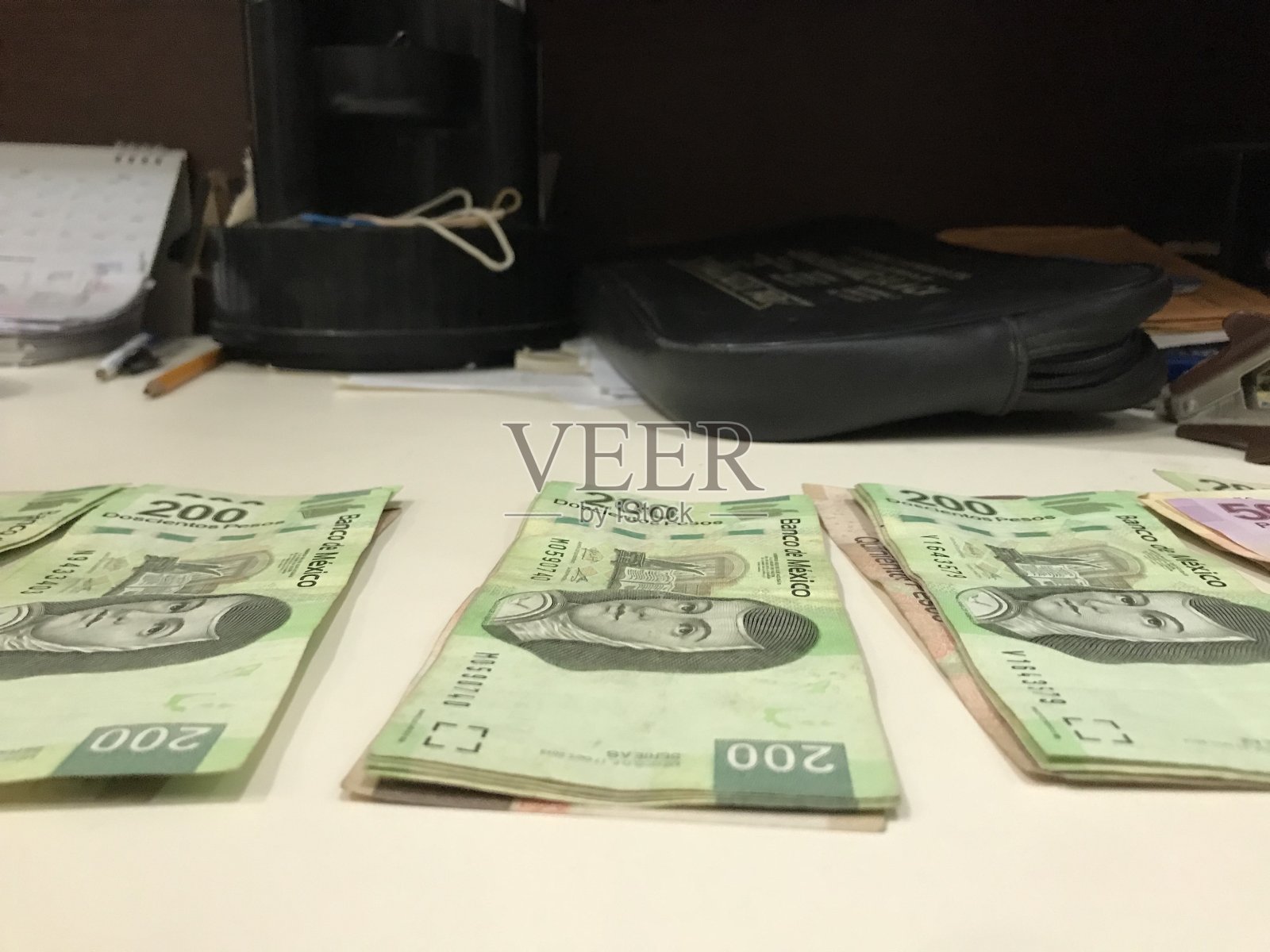 在一间小型商业办公室里，米色的桌子上放着几张墨西哥比索照片摄影图片