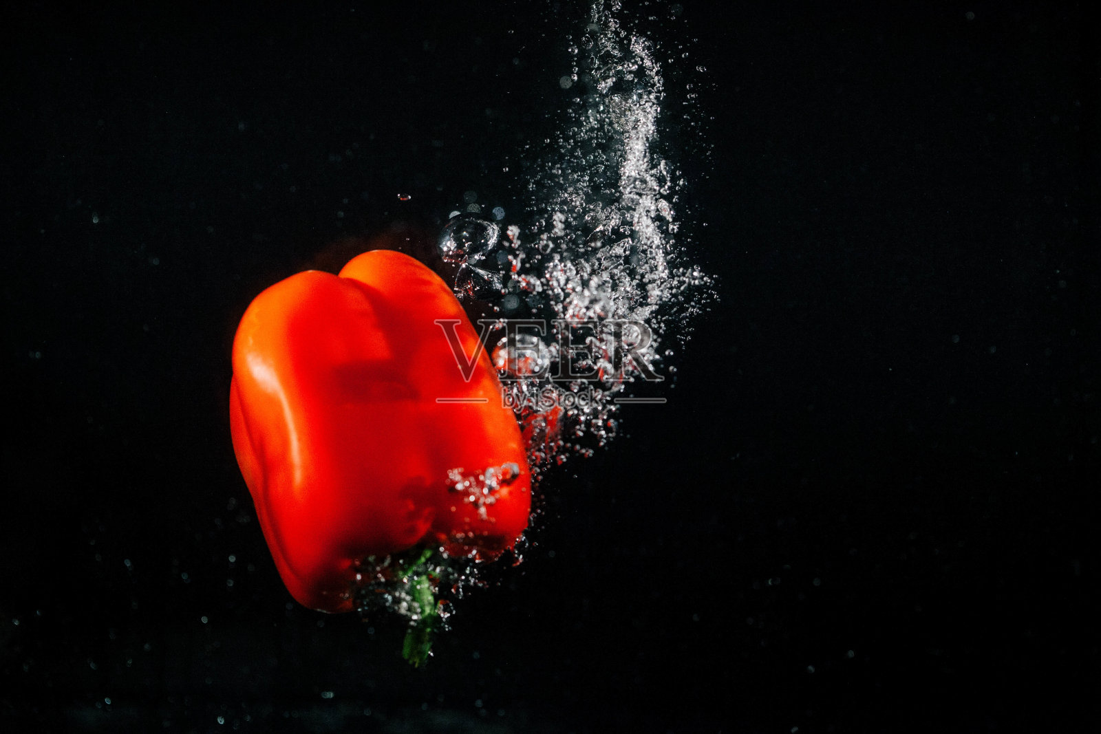 红辣椒落入水中，周围的气泡随之升起照片摄影图片