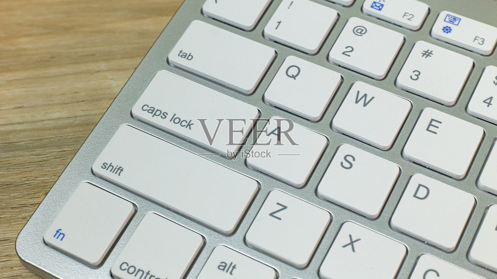 银色键盘放在木桌上平躺的形象。照片摄影图片