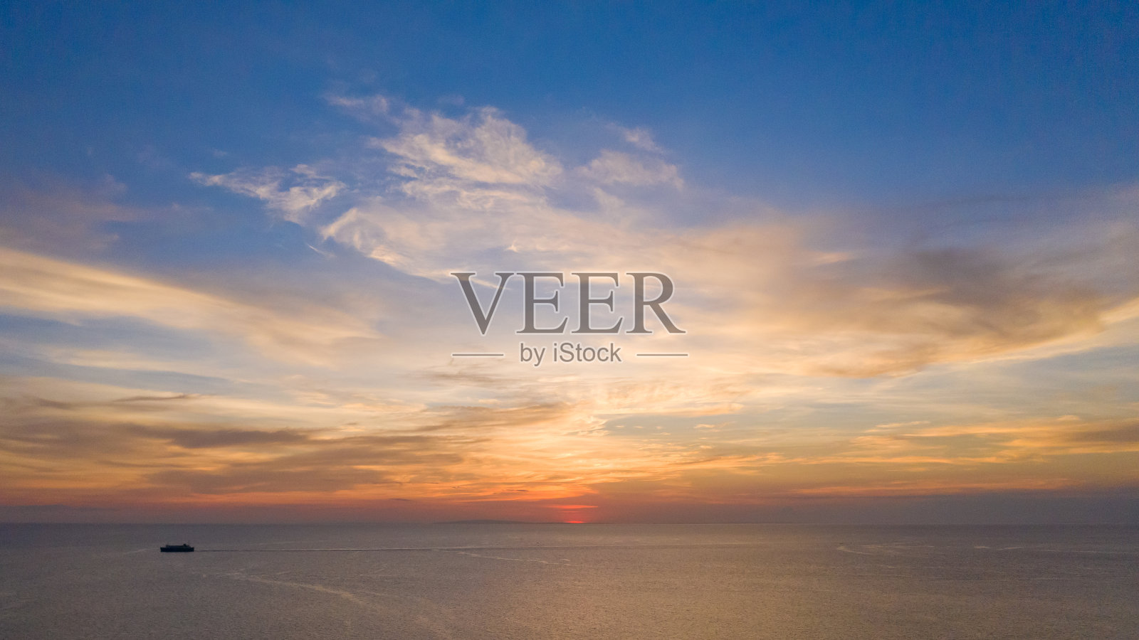 海面上的夕阳和远处的帆船照片摄影图片