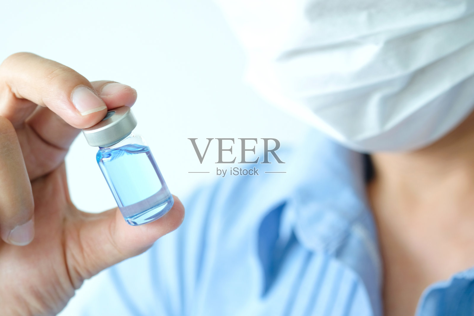 医生的手，他拿着一瓶抗逆转录病毒药物，蓝色的水。健康和医学概念照片摄影图片