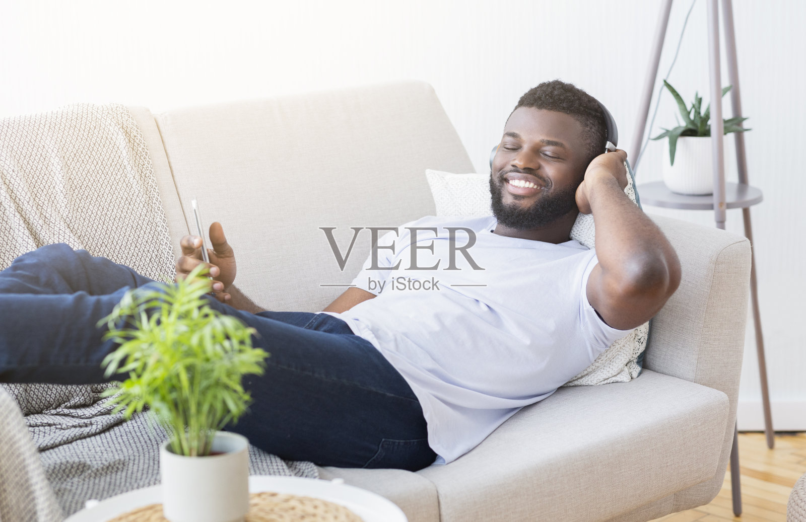 英俊的年轻人戴着耳机在电话里听音乐照片摄影图片