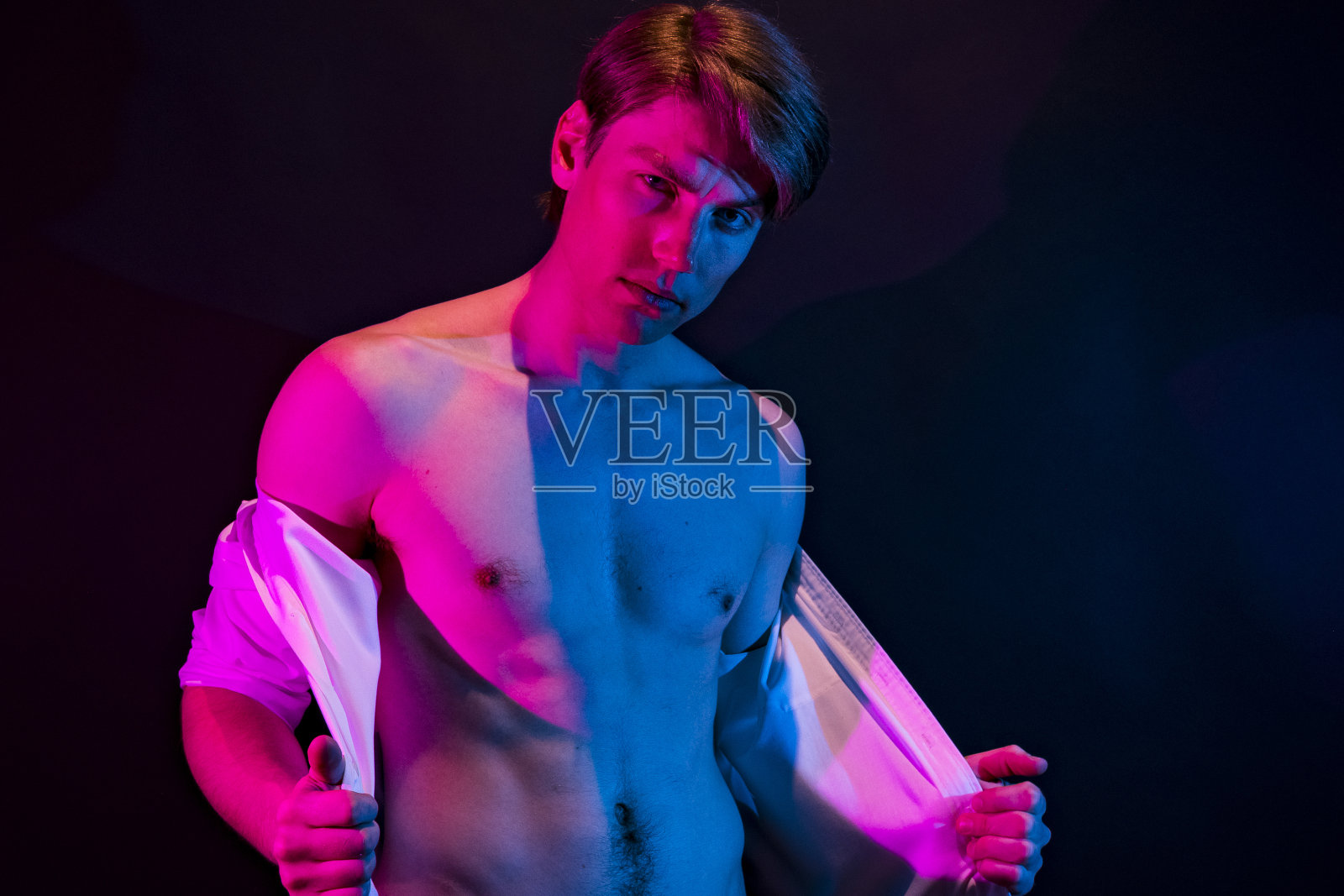 性感的男人展示他的胸部，他的衬衫解开照片摄影图片