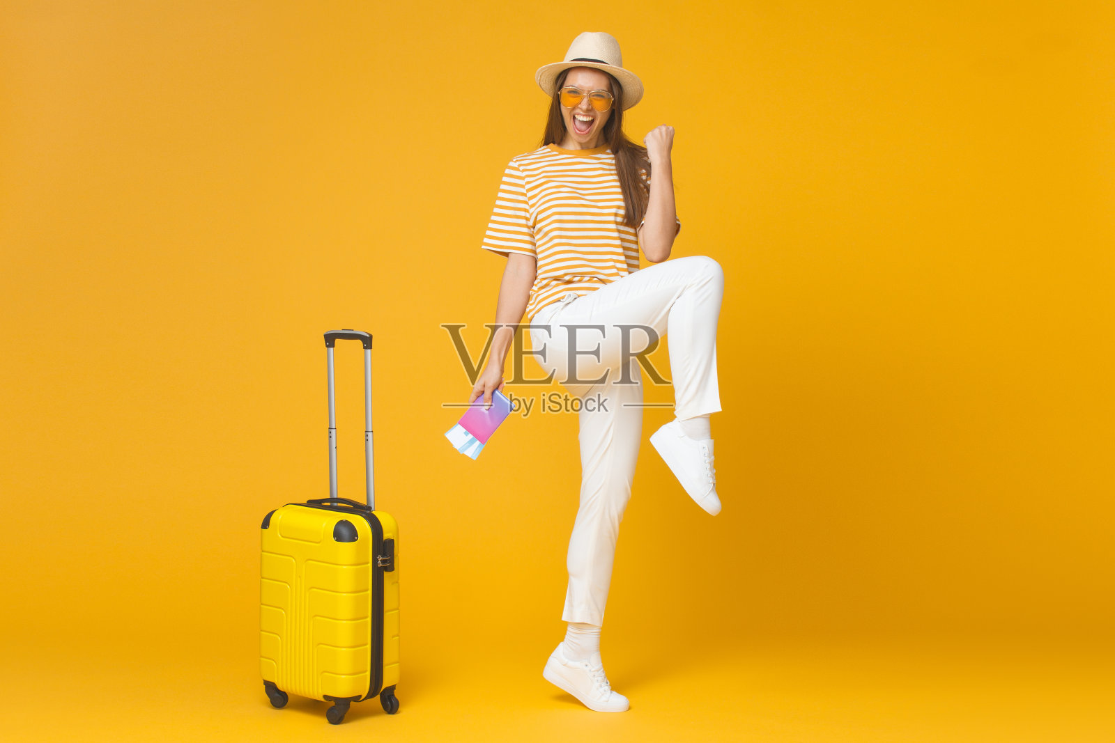 快乐的年轻女子准备好旅程和感受成功，孤立在黄色的背景照片摄影图片