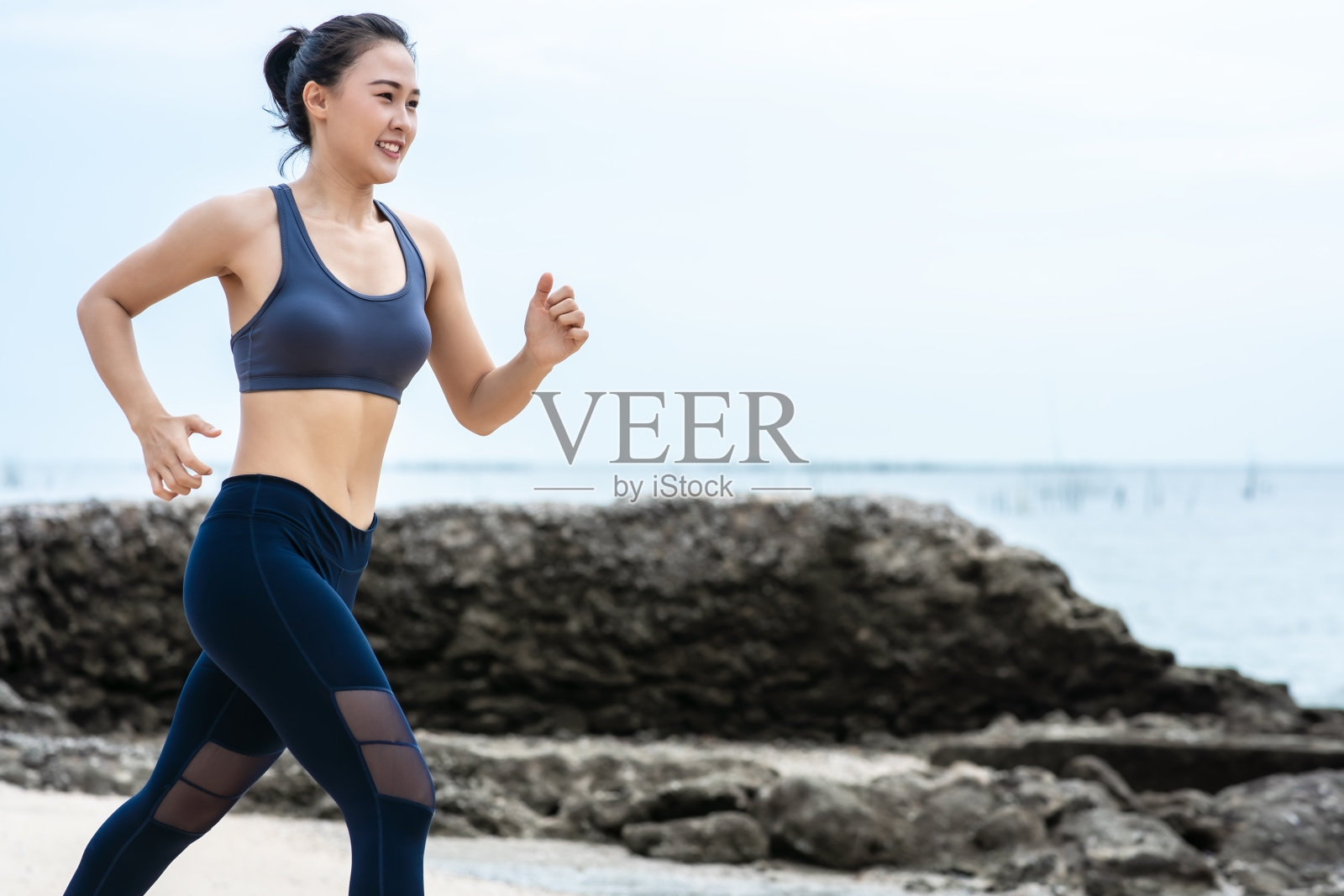 年轻的亚洲女人在沙滩上跑步。女孩在海边慢跑锻炼照片摄影图片