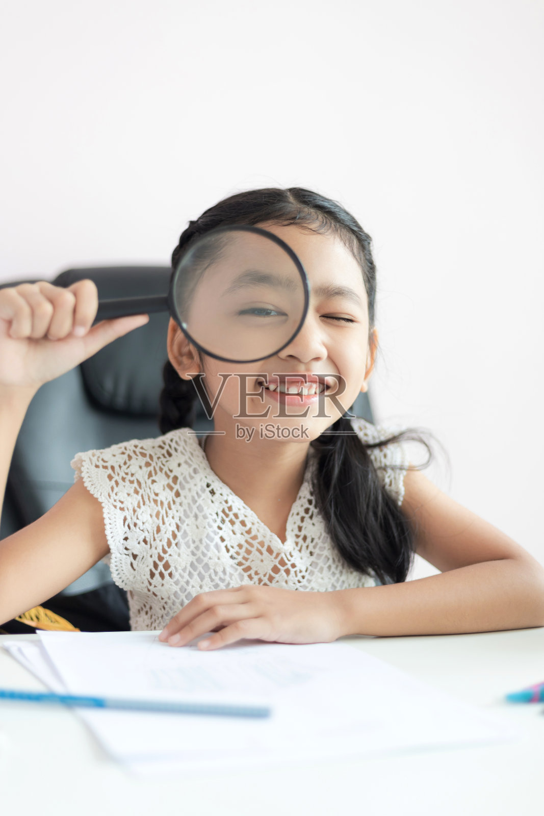 亚洲小女孩用放大镜做作业，带着幸福的微笑为教育理念选择焦点浅景深照片摄影图片