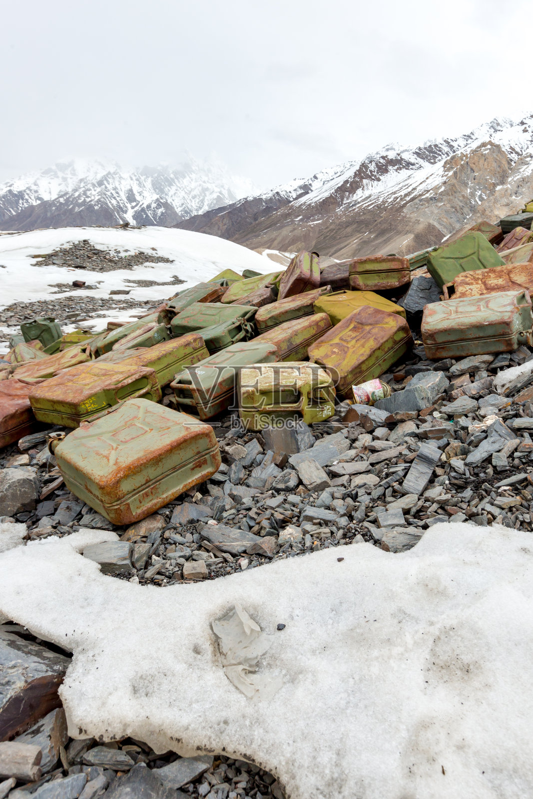 垃圾散落在雪山上。让我们拯救地球，回收多余的垃圾。照片摄影图片