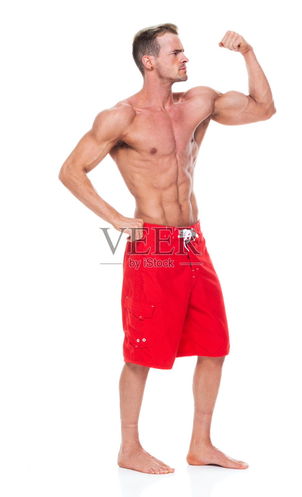 英俊的肌肉男子谁是赤膊和穿着板短裤和弯曲他的肌肉照片摄影图片