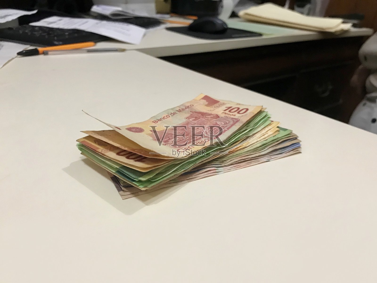 在一间小企业办公室里，米色的桌子上放着许多墨西哥比索照片摄影图片
