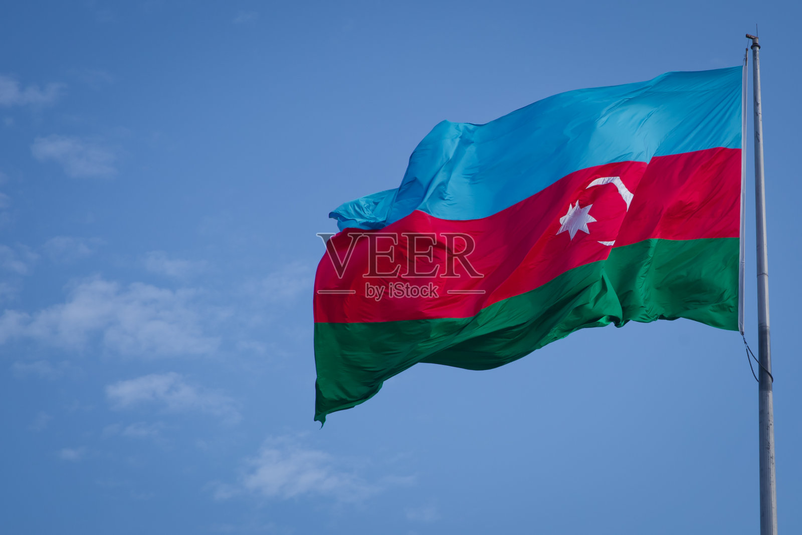 蓝天背景下的阿塞拜疆国旗。在多云的天空中飘扬的阿塞拜疆国旗。阿塞拜疆国旗的织物质地照片摄影图片