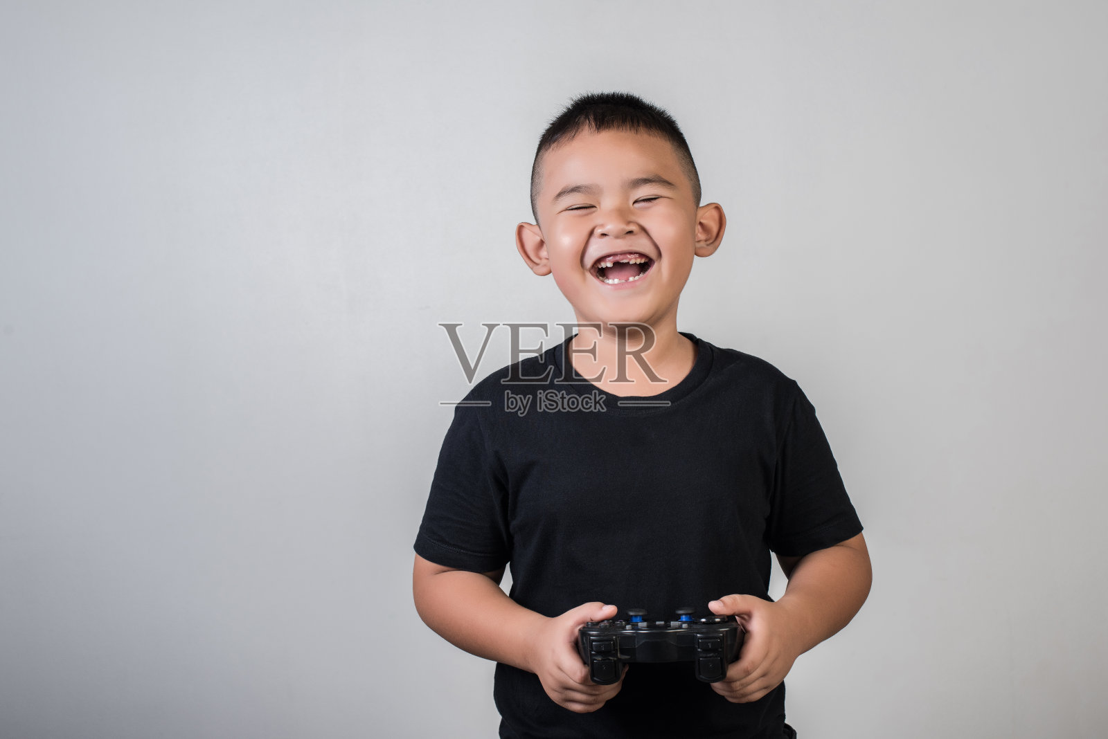 快乐的男孩在影楼用控制器玩电脑游戏照片摄影图片