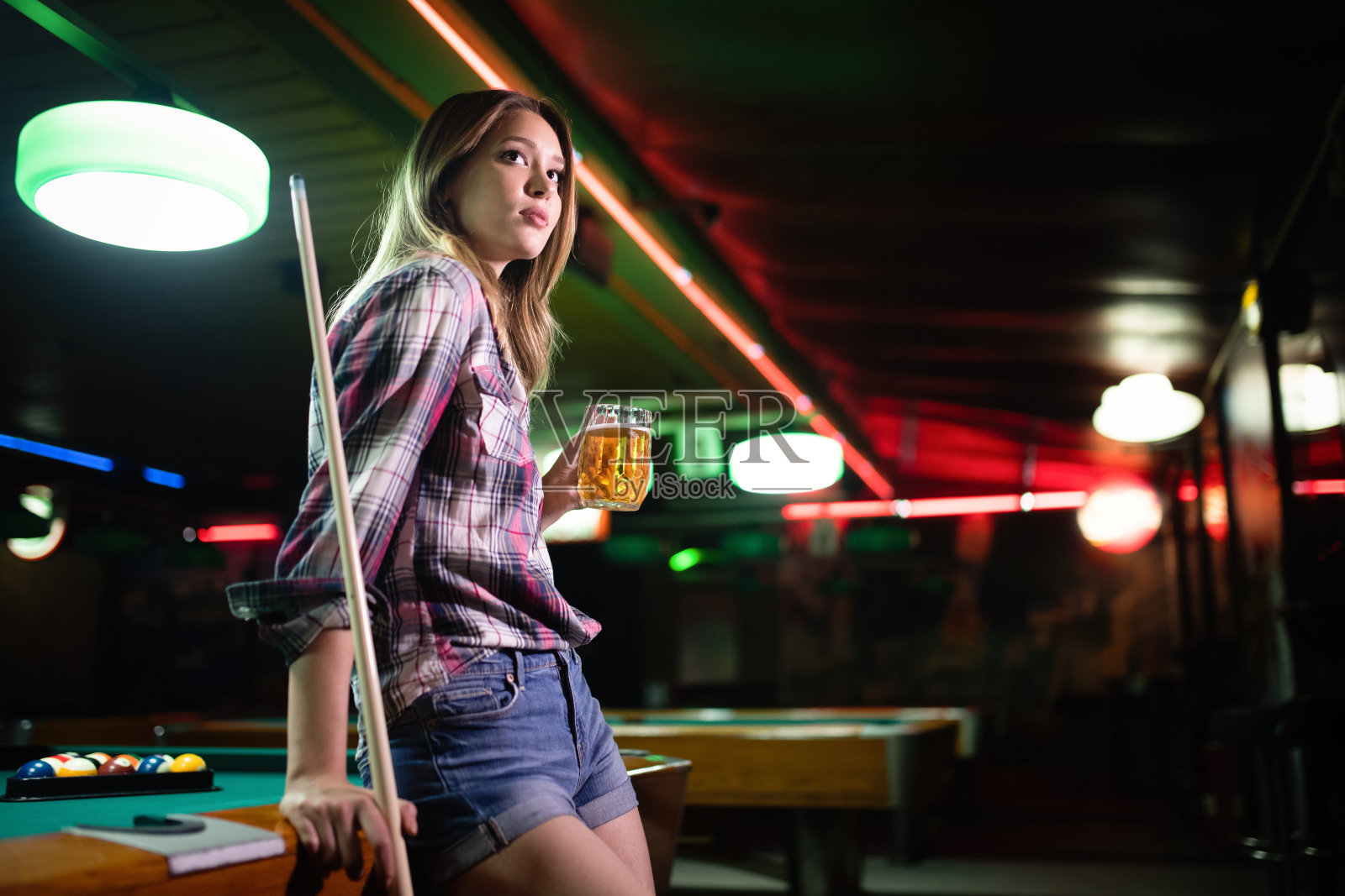 年轻漂亮的女人有乐趣和打台球在一个俱乐部照片摄影图片