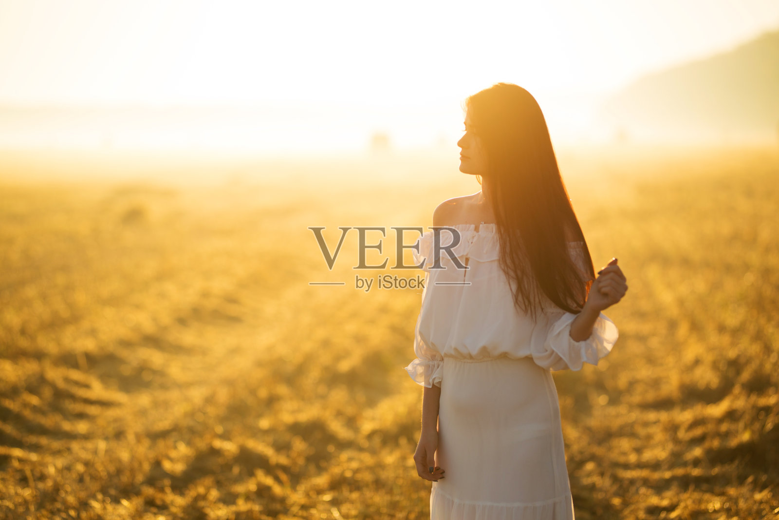 夏天是一个伟大的梦想时间。夕阳下的年轻女子照片摄影图片