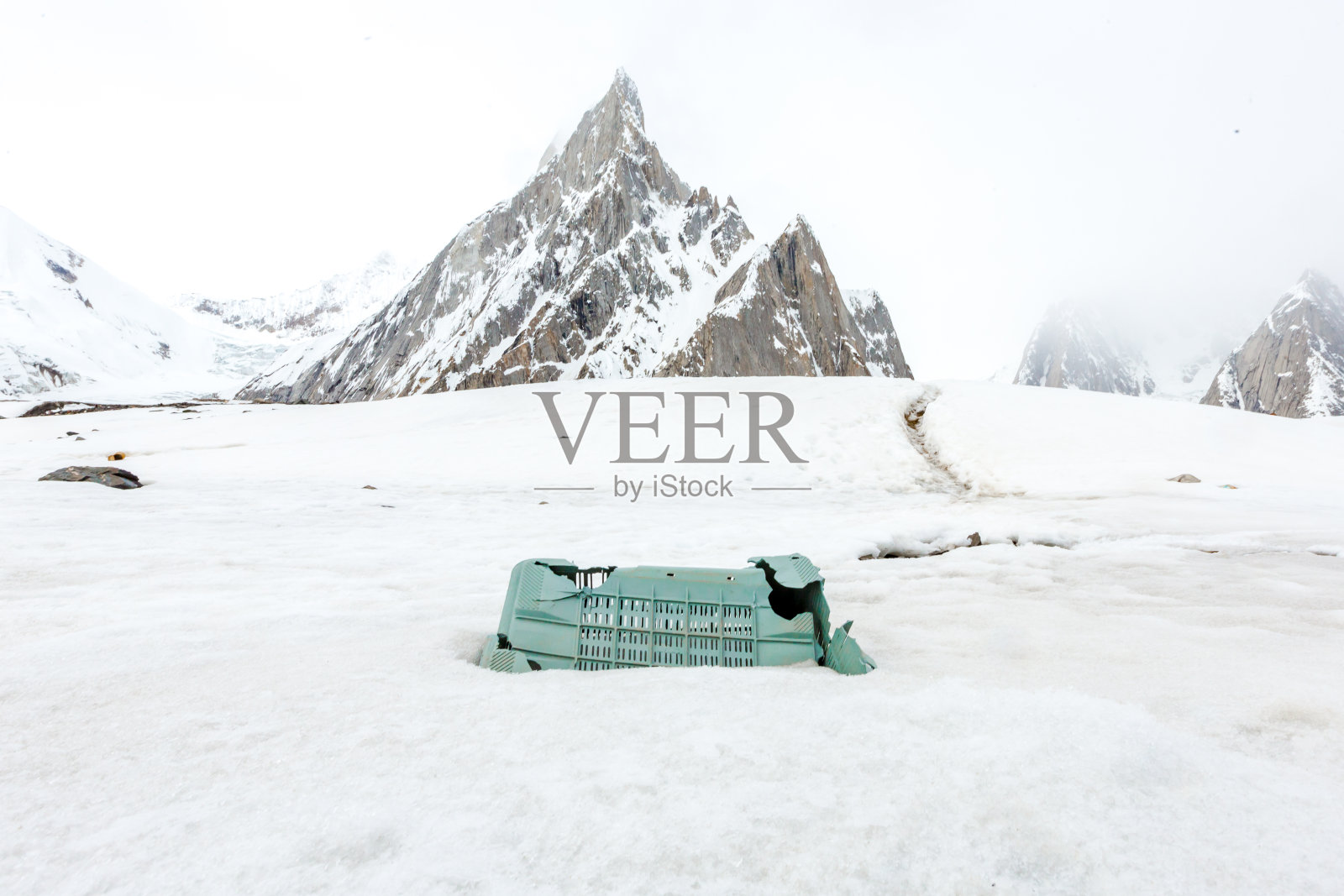 垃圾散落在雪山上。让我们拯救地球，回收多余的垃圾。照片摄影图片