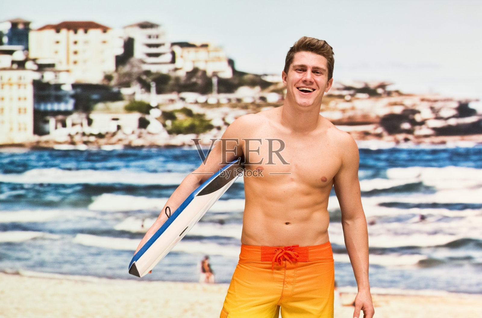 年轻的成年男子赤膊站在沙滩上，拿着木板照片摄影图片