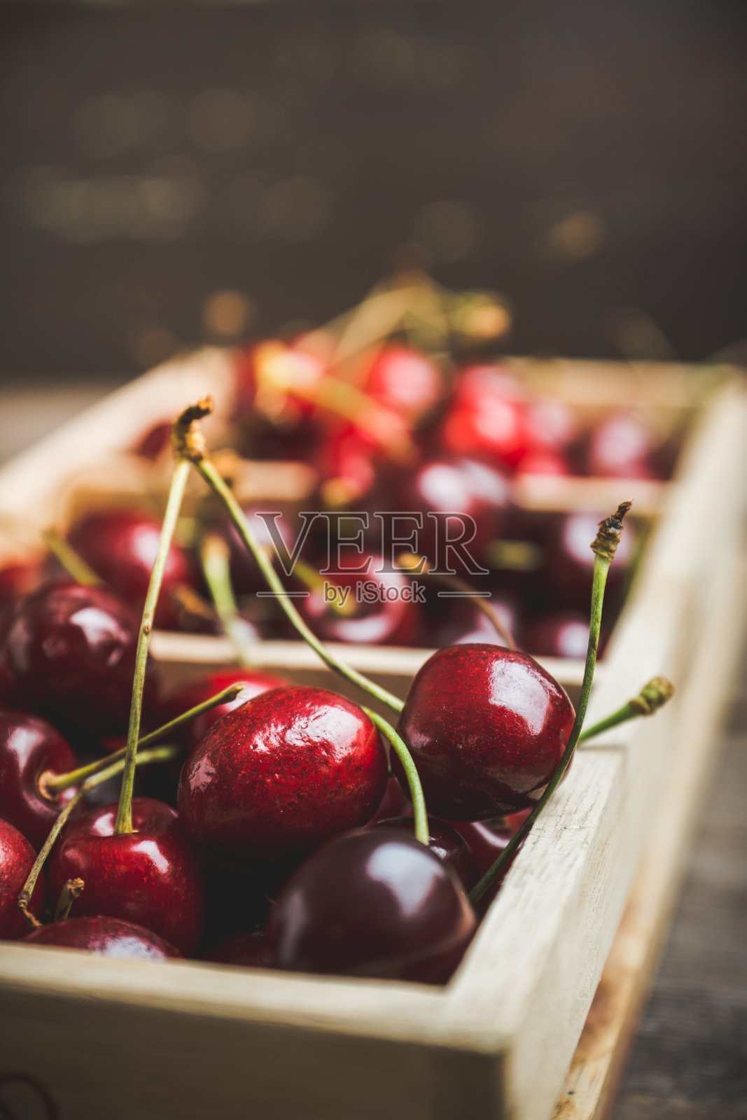 熟透多汁的樱桃装在木箱里，背景是乡村的黑暗照片摄影图片