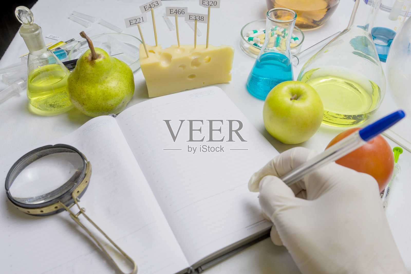 食品安全检查员正在检验市场上的水果。带研究报告的笔记本和蓝笔放在实验台上，具有选择性聚焦的效果照片摄影图片
