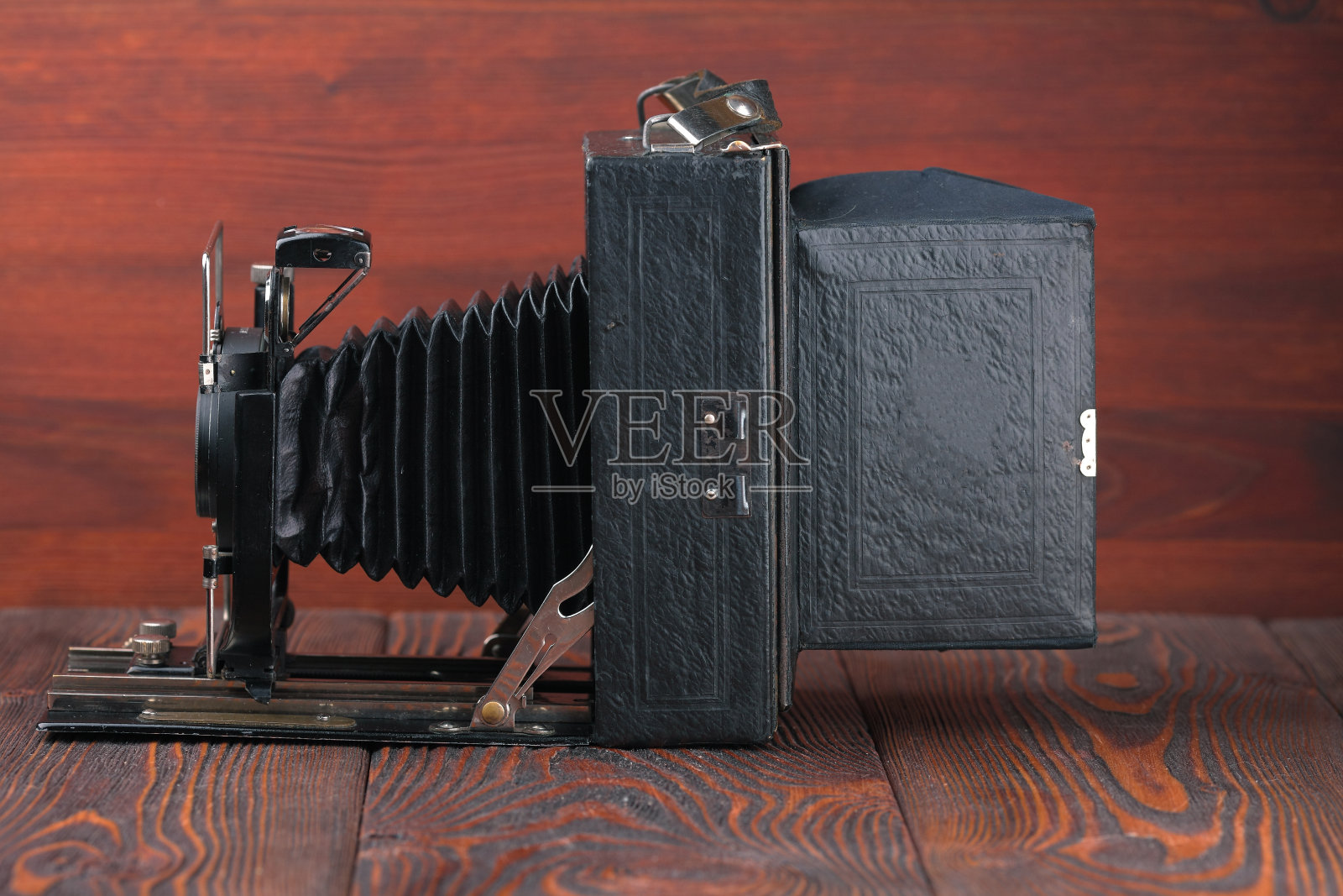 在红木背景上的老式大画幅胶卷照相机。照片摄影图片