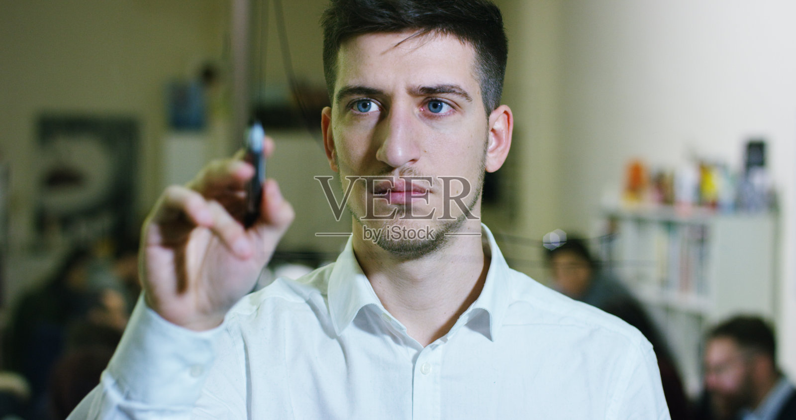 一个微笑的年轻人的肖像在一个深思熟虑和创造性的机构与彩色的笔记和计划挂在玻璃后和劳动人民。照片摄影图片