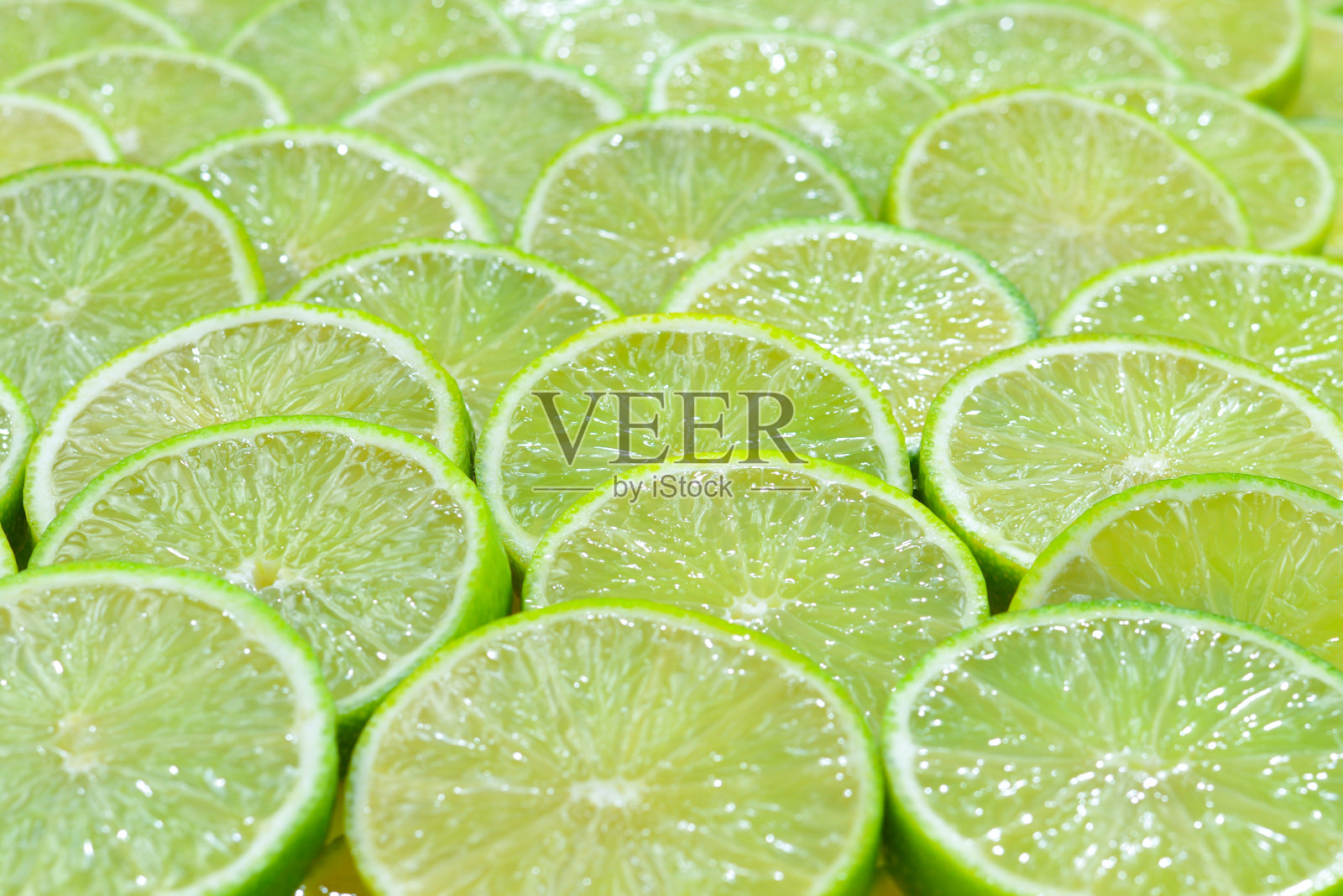 新鲜的酸橙片作为背景。照片摄影图片