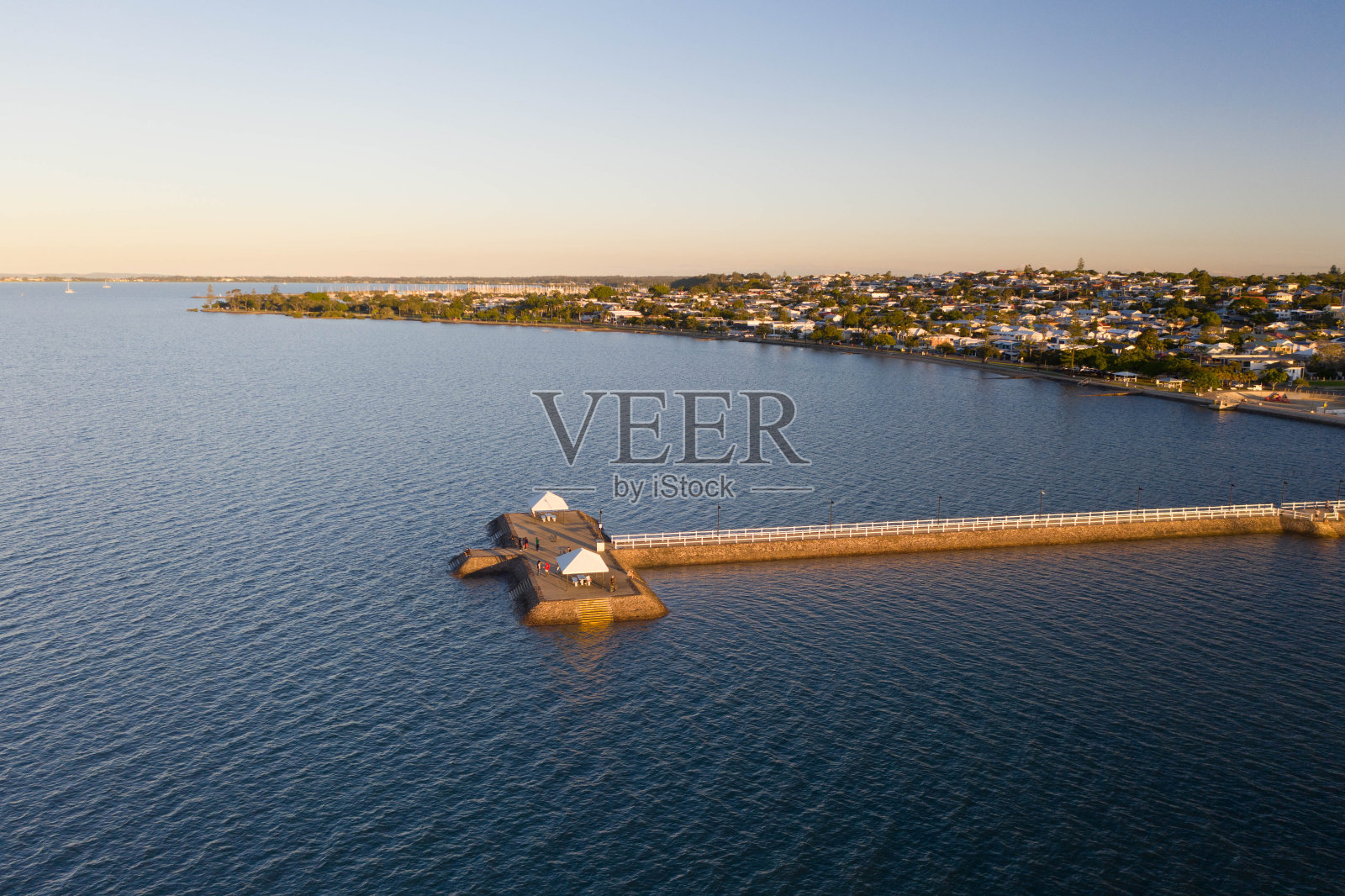美丽的空中日落在一个沿海城镇，长长的码头为渔民，步行者，慢跑者，家庭和老人照片摄影图片