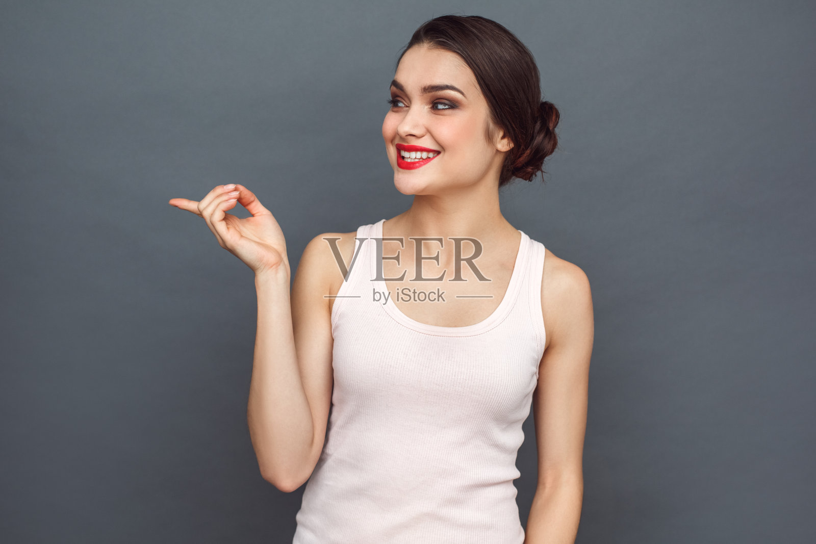 自由泳。女人孤立地站在灰色指着一边好奇地微笑照片摄影图片