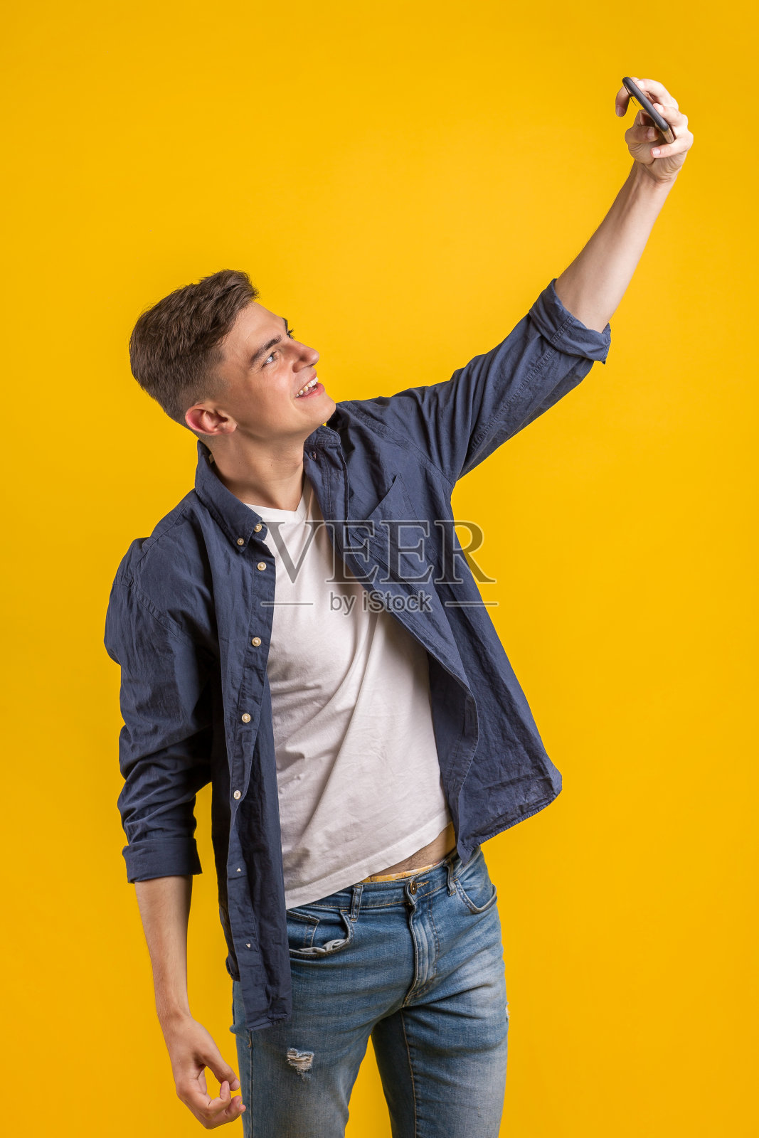 一名身穿格子衬衫的兴高采烈的年轻人孤立地站在橙色背景下自拍照片摄影图片