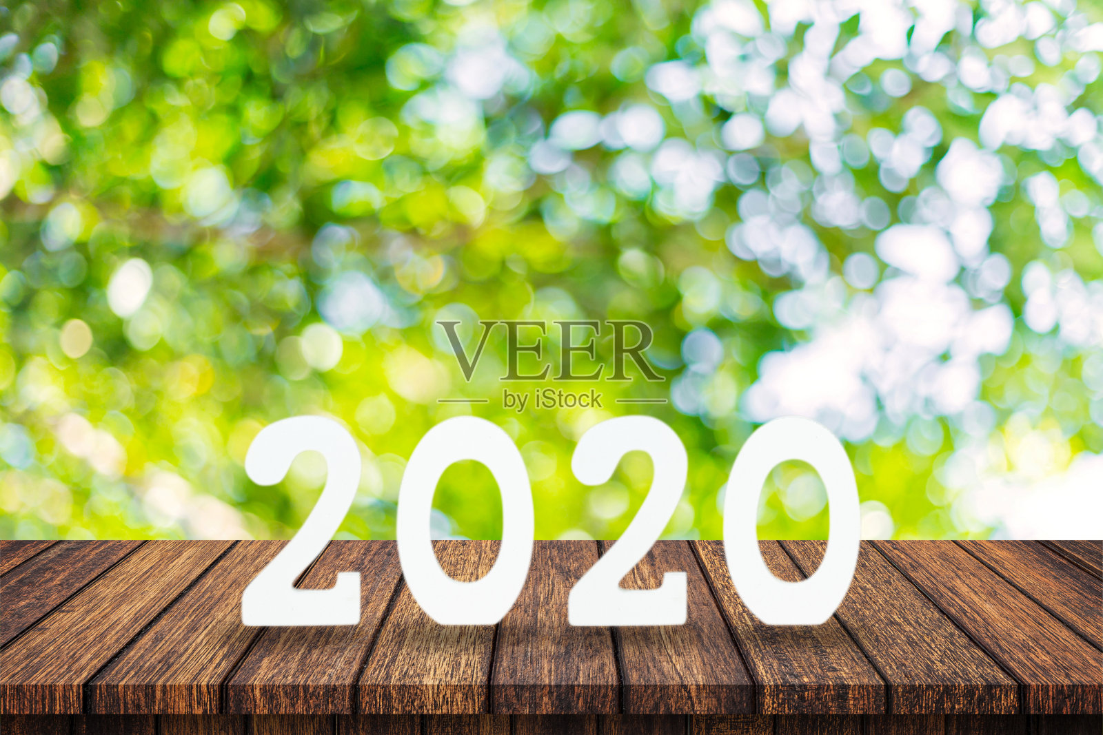 2020年新年概念——桌子上的木字“2020”和模糊的绿色灯光背景照片摄影图片