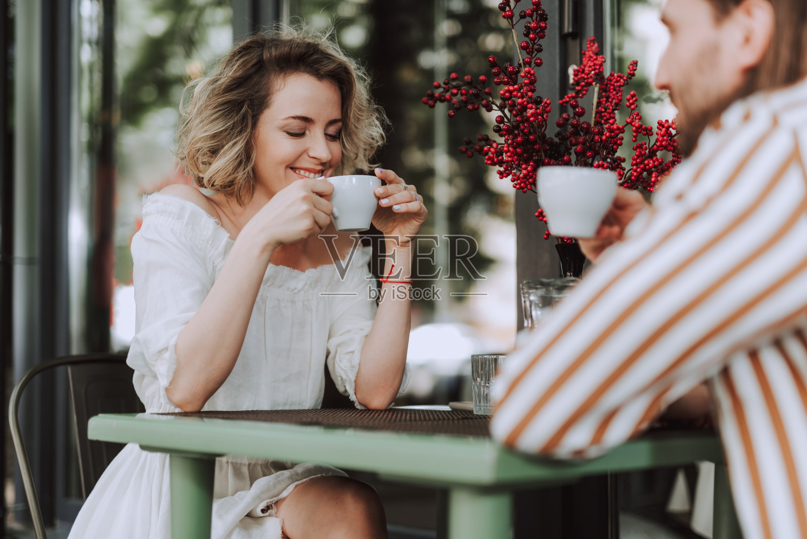 迷人的年轻女子和她的朋友在户外咖啡馆喝咖啡照片摄影图片