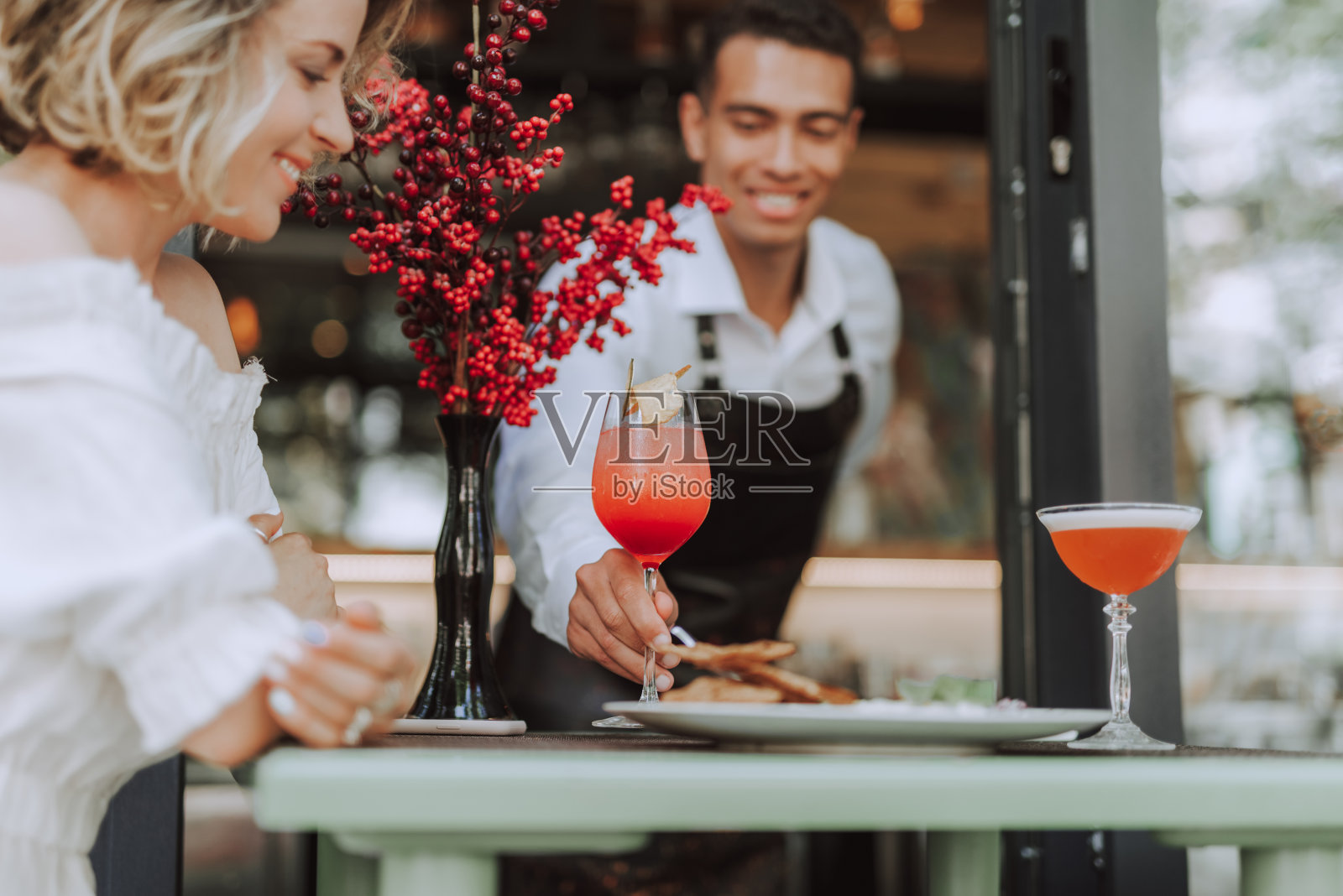 调酒师在户外咖啡馆为年轻女子斟酒照片摄影图片