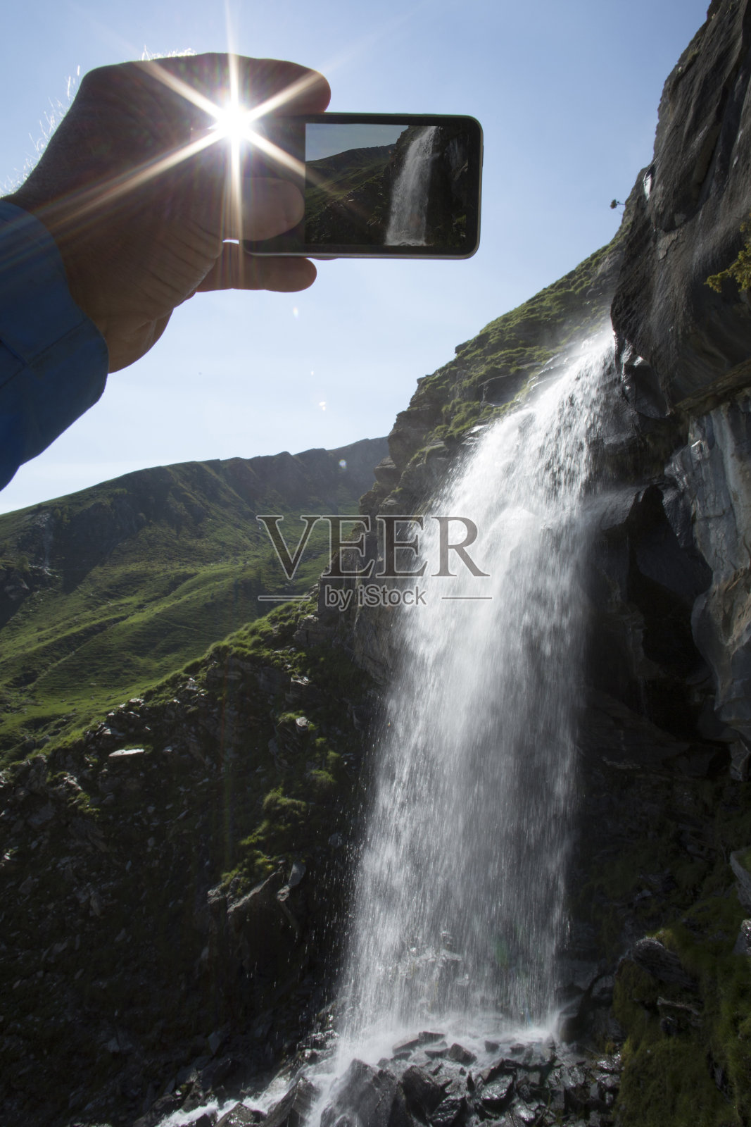 徒步旅行者在阳光下拍摄瀑布的照片照片摄影图片