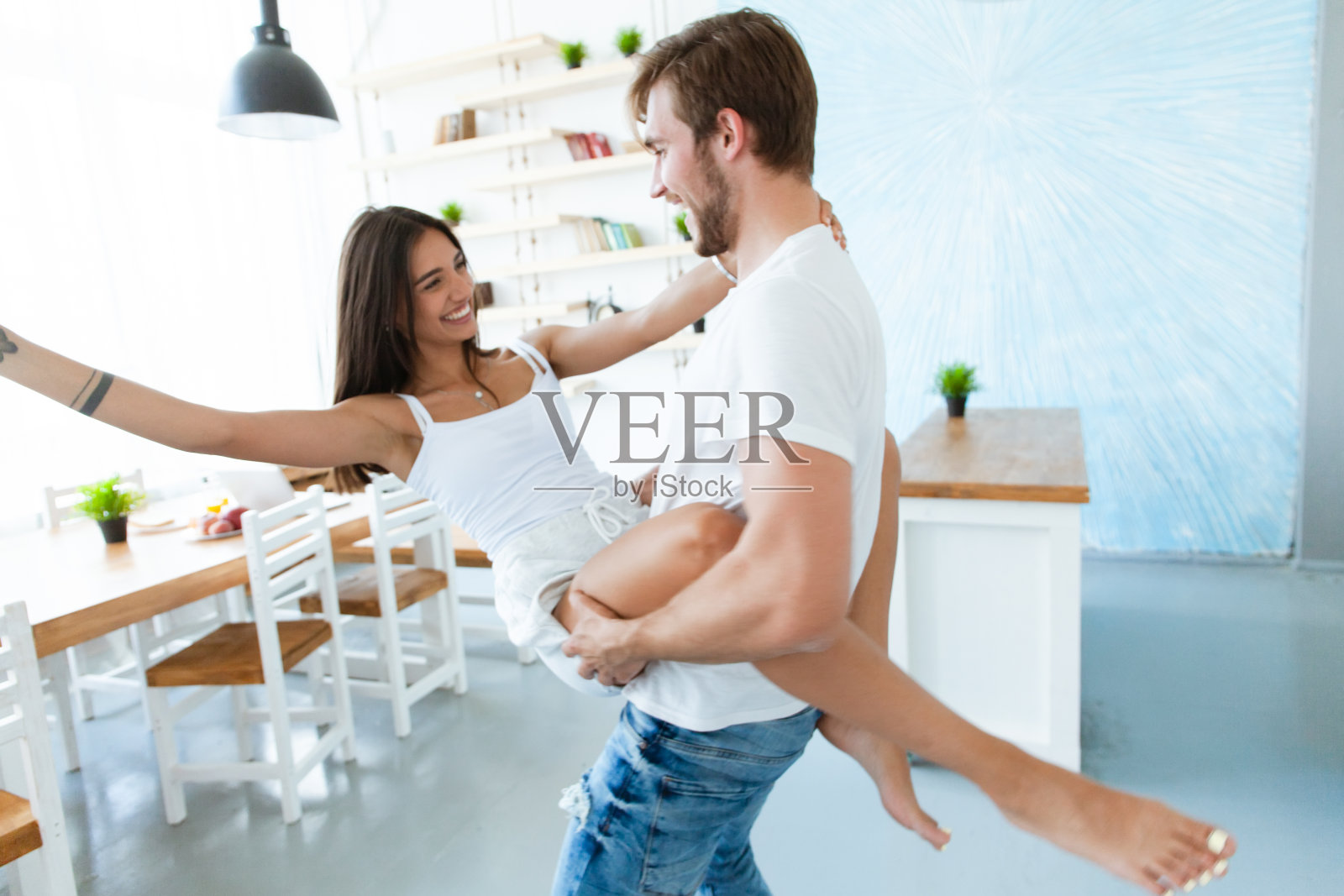 在家的浪漫情侣：年轻女子和英俊男子在现代厨房里共舞照片摄影图片