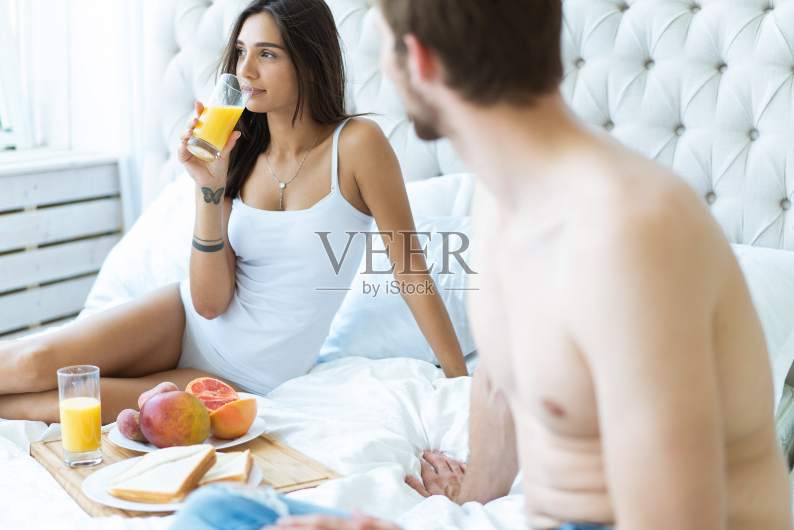 早上好!在床上吃健康早餐。一对年轻美丽的情侣在吃早饭前坐在床上。照片摄影图片
