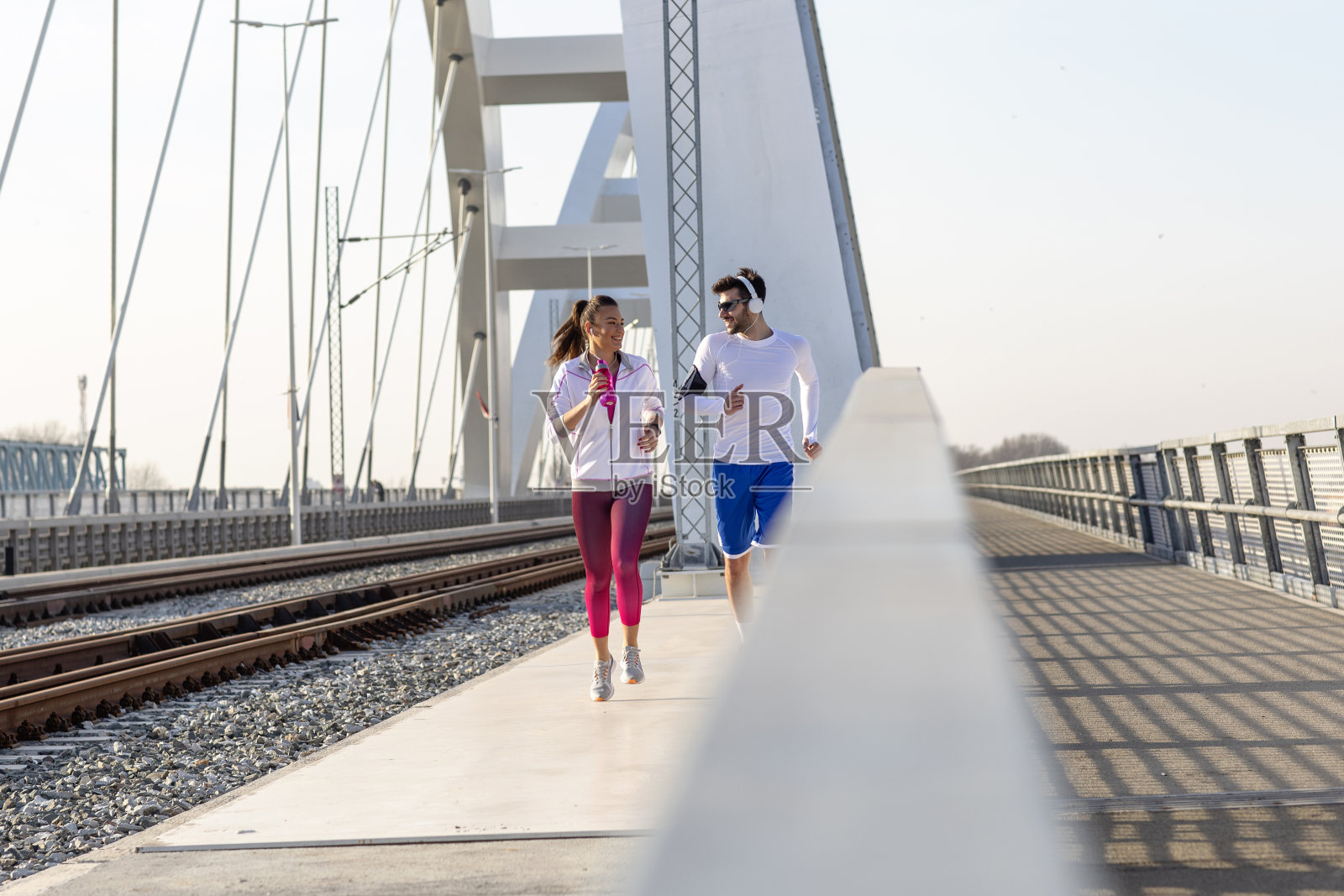 一对戴着耳机在桥边慢跑的情侣照片摄影图片