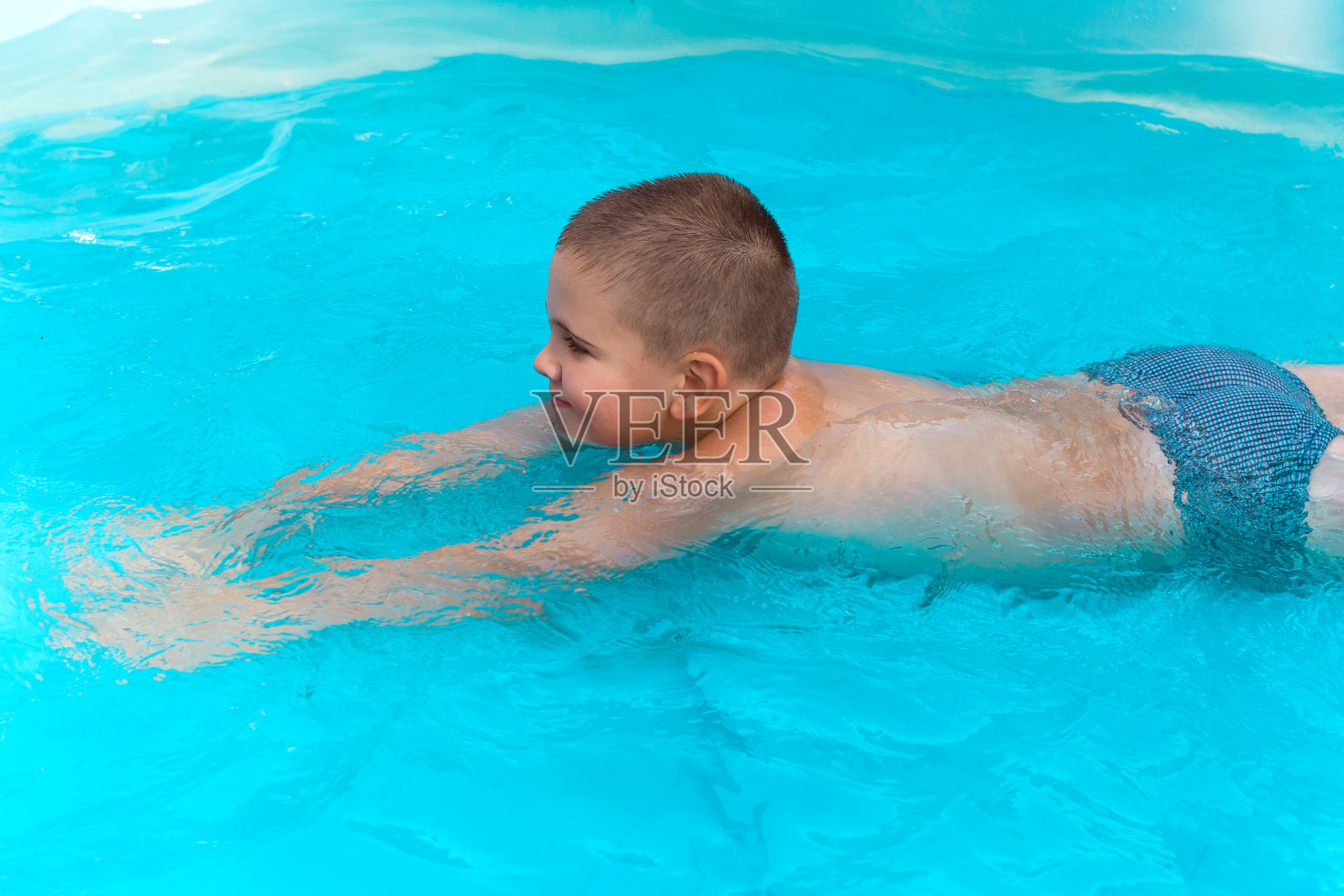 可爱的小男孩在绿松石般的池子里游泳照片摄影图片