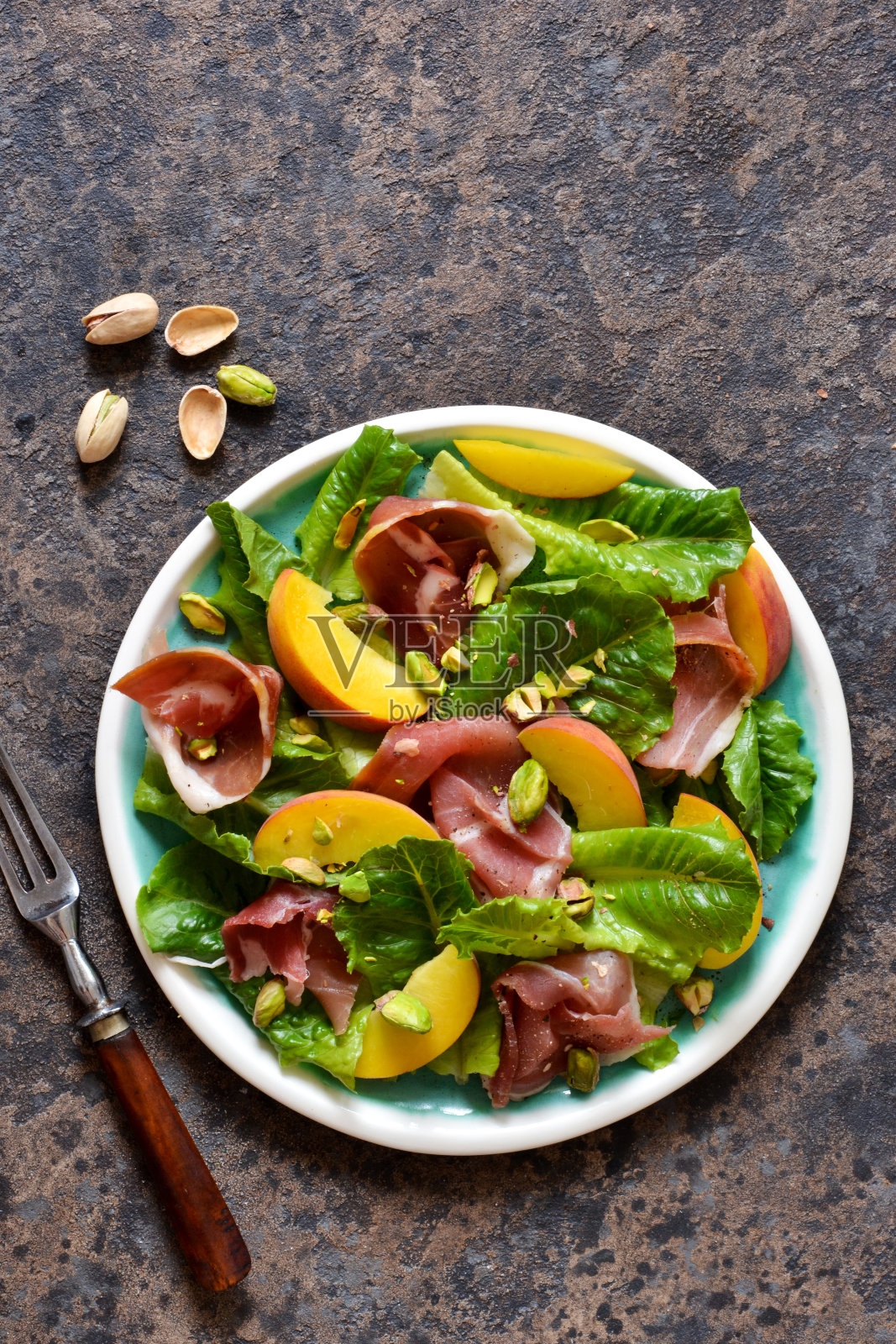 混凝土背景下的新鲜火腿沙拉配辣椒和开心果。从以上观点。照片摄影图片