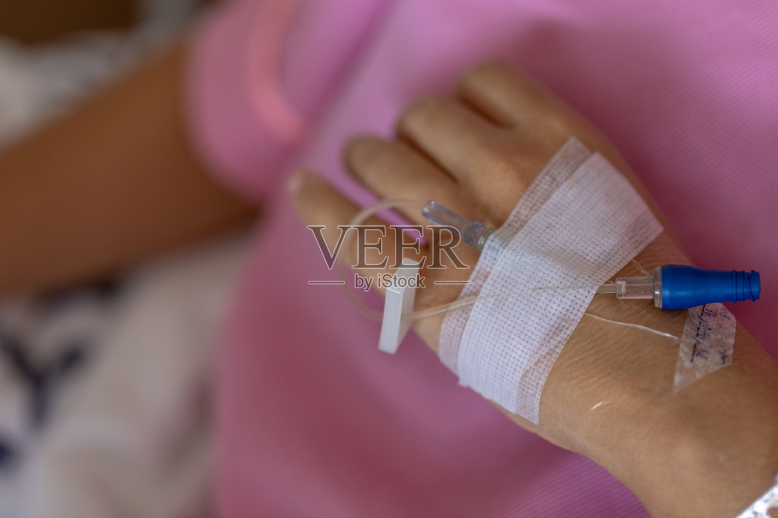 近手妇女患者的手注射生理盐水和躺在医院的康复床上。照片摄影图片