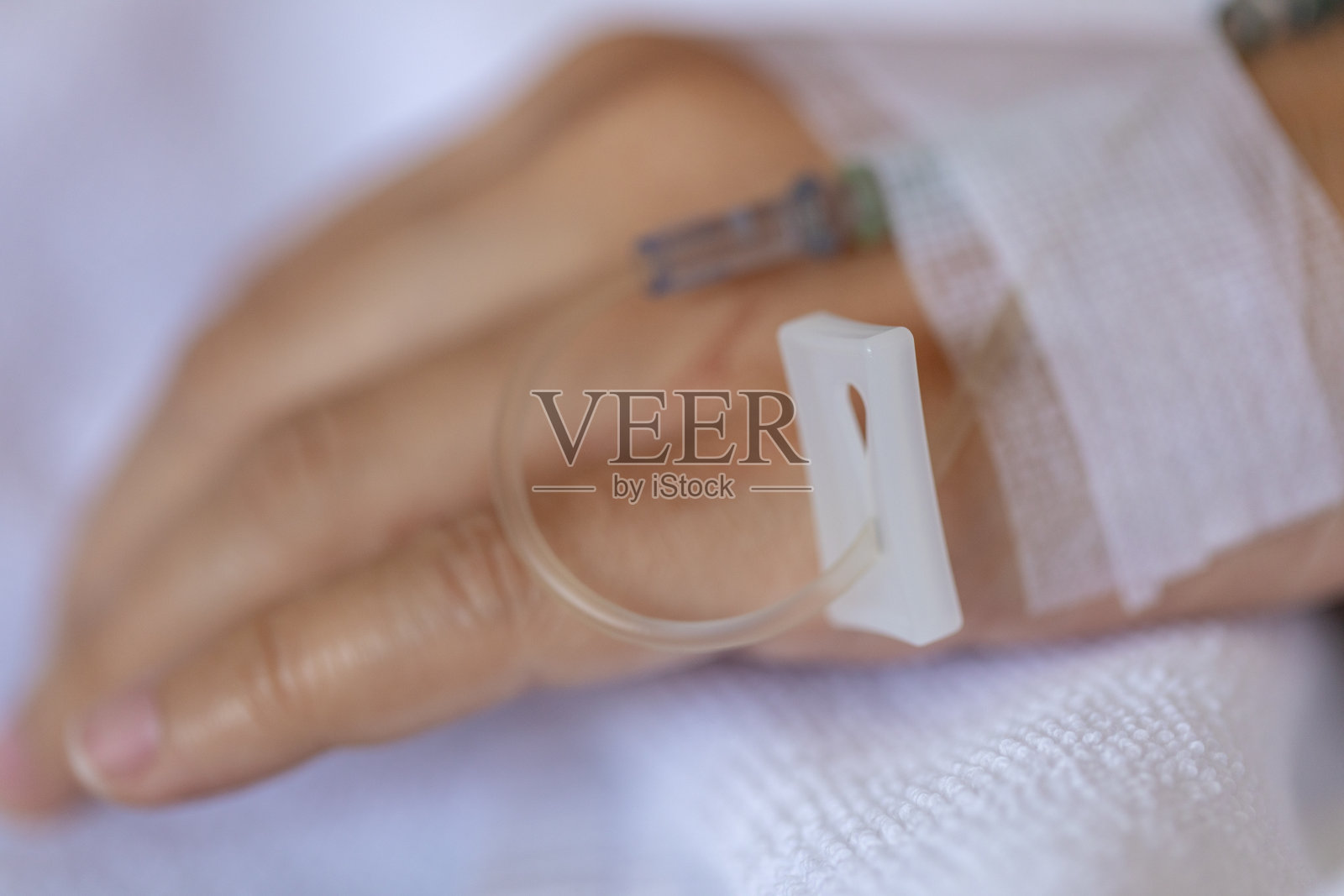 近手妇女患者的手注射生理盐水和躺在医院的康复床上。照片摄影图片