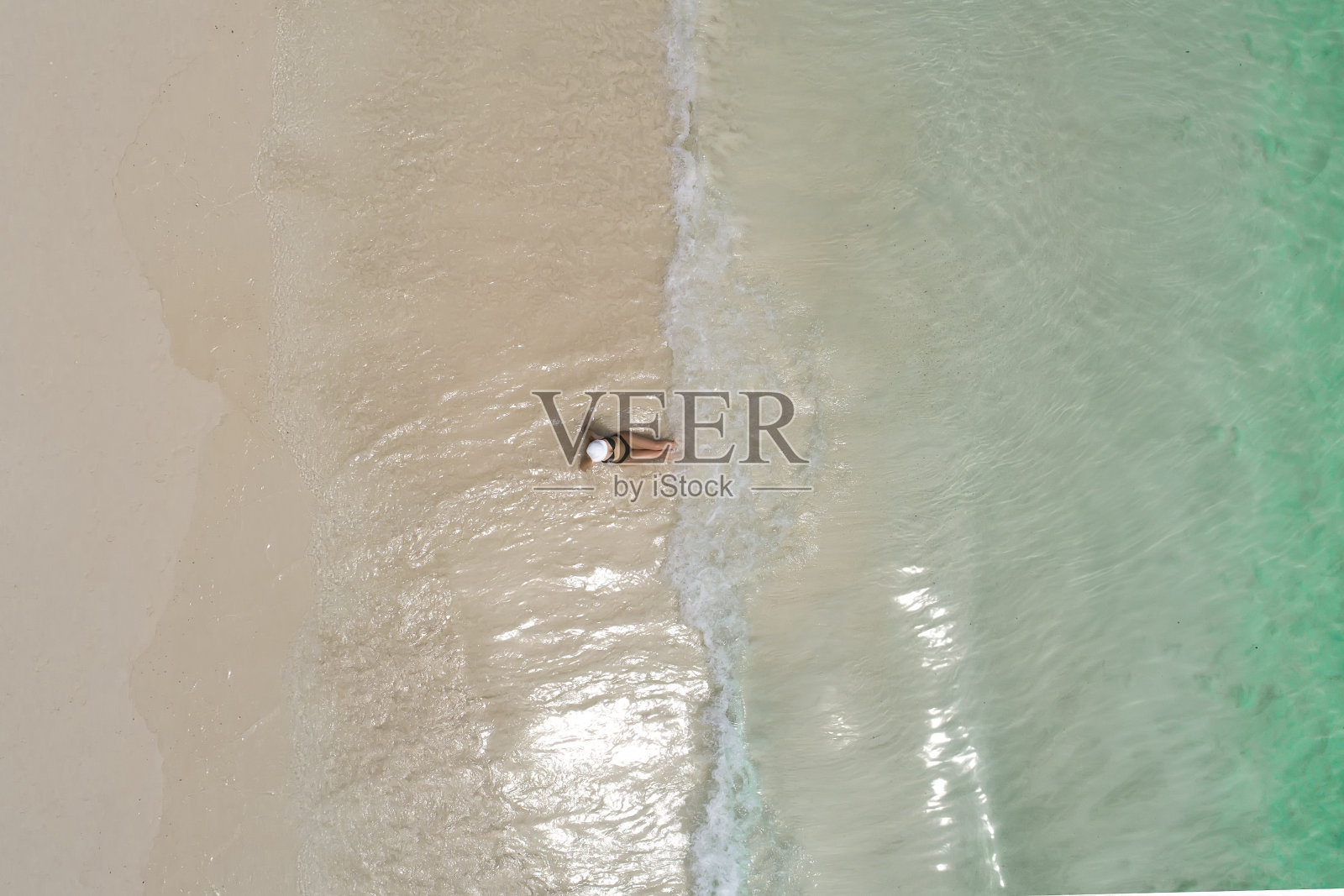 无人机鸟瞰美丽的女孩在阳光明媚的热带海滩上玩耍。塞舌尔照片摄影图片