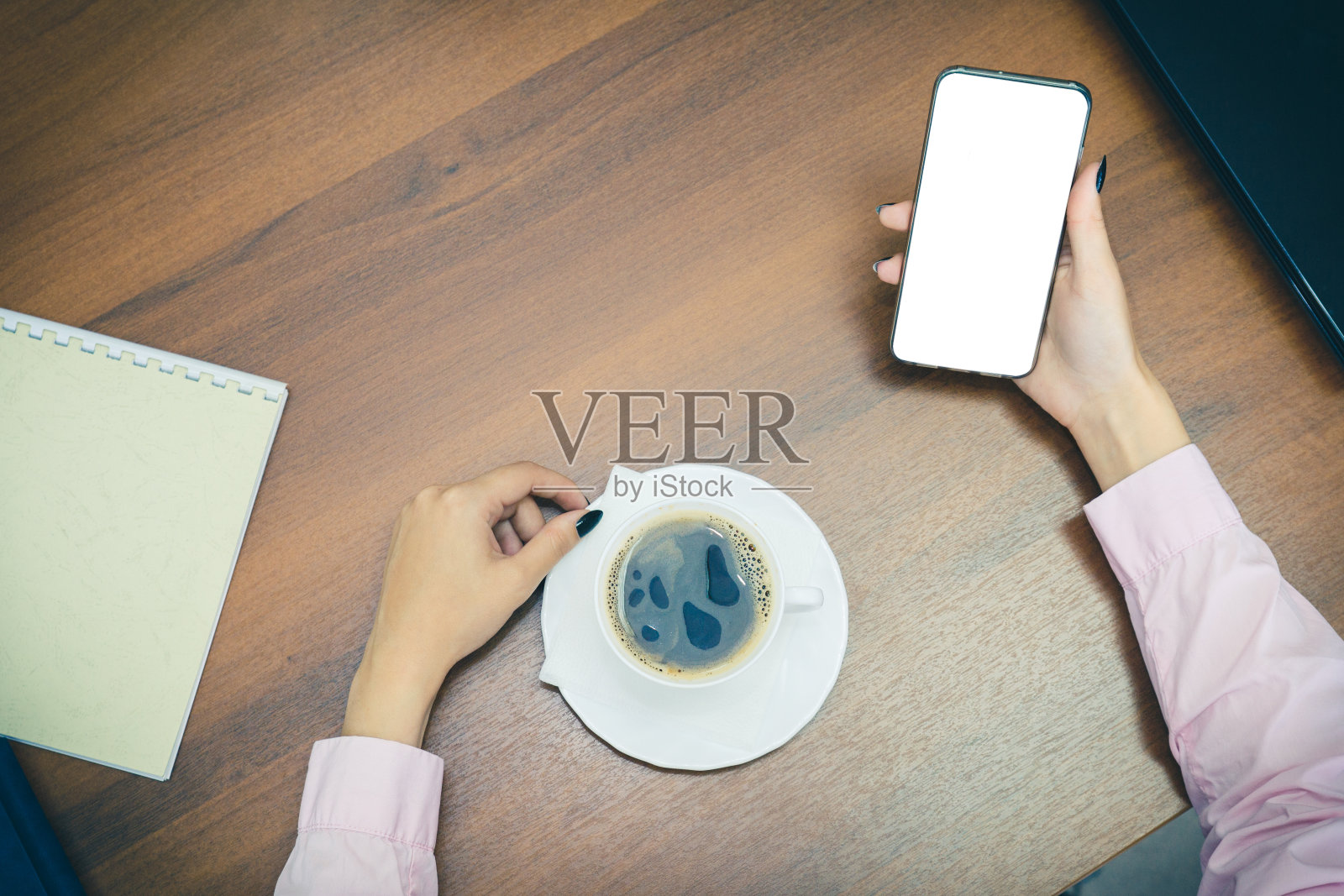 商务谈判后的休息时间。在办公室工作的休息时间。一杯咖啡，手放在桌上，俯视图。拿着一杯咖啡的女人的手照片摄影图片