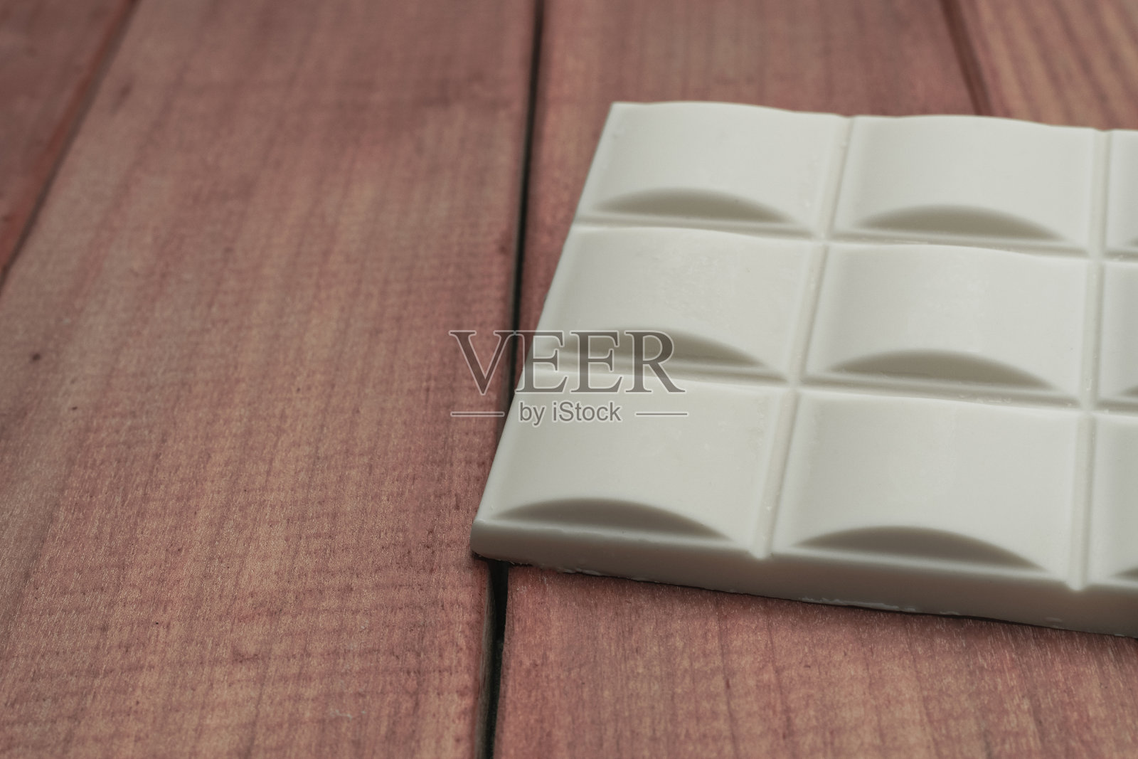 近距离看，白色巧克力放在红色木制桌子的背景上。宏观的观点。照片摄影图片