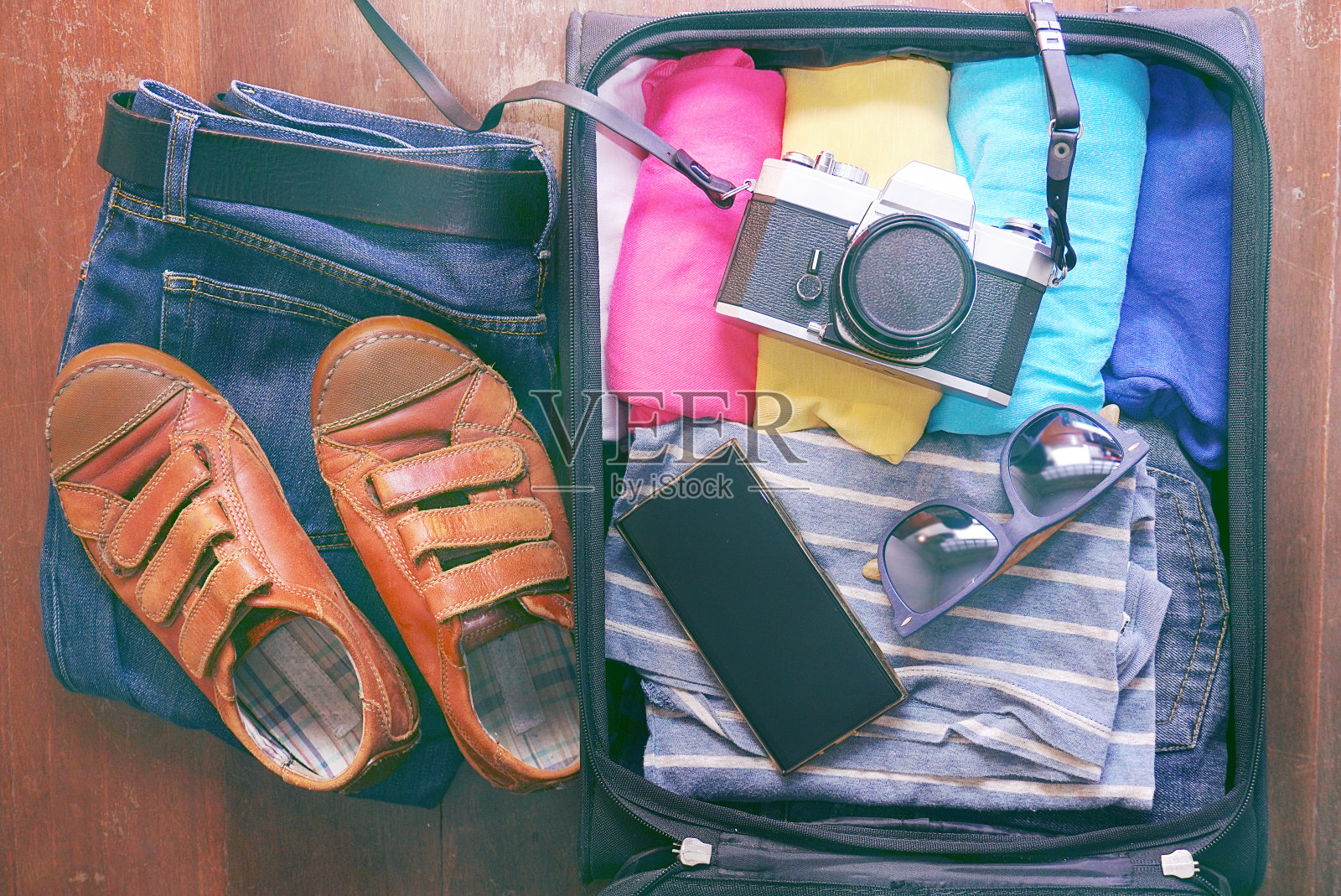 Topview打开旅行袋，有衣服和配件的木材背景照片摄影图片