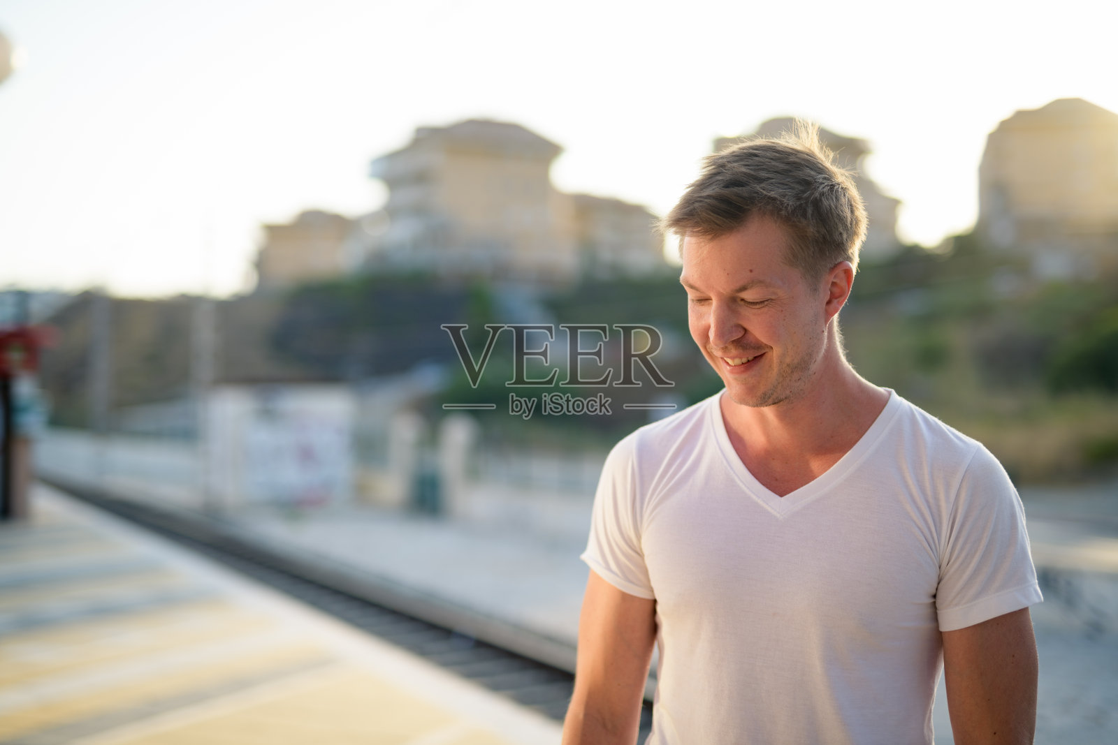 年轻英俊的游客在火车站微笑和思考照片摄影图片