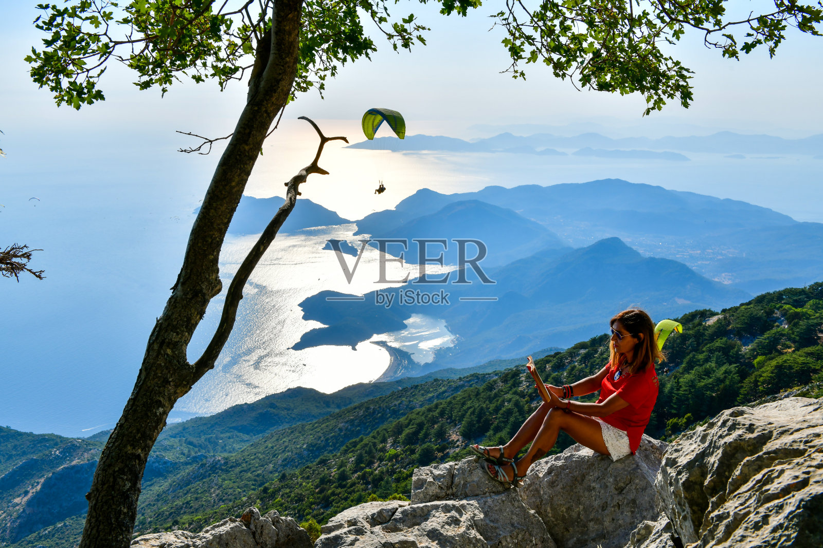 在山顶读书的女人。照片摄影图片