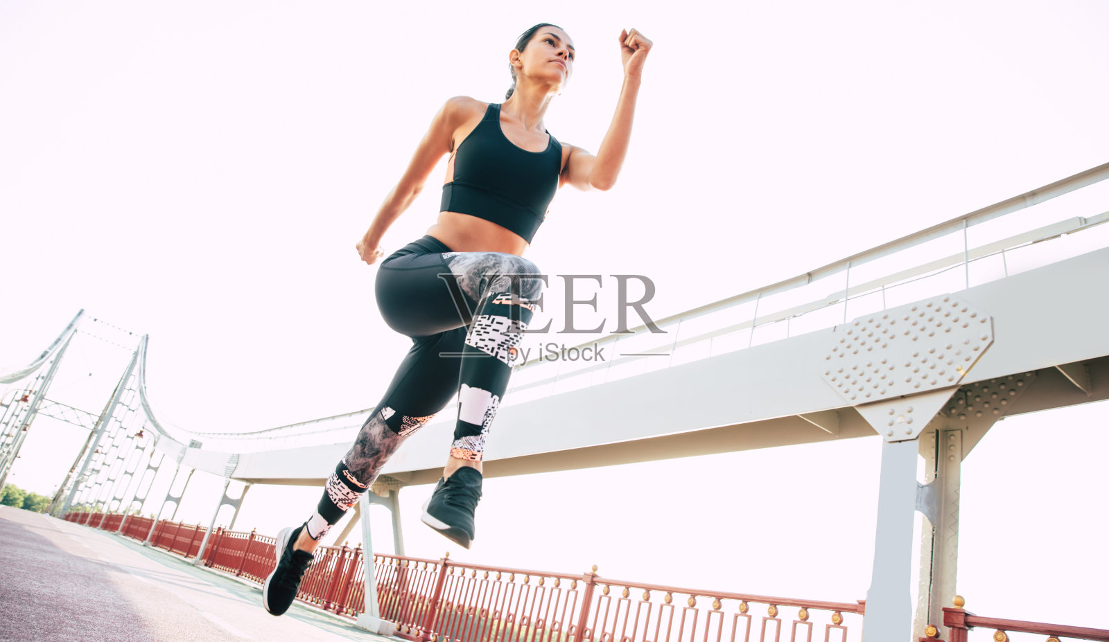 自信而专注的年轻女子正在户外的桥上慢跑照片摄影图片