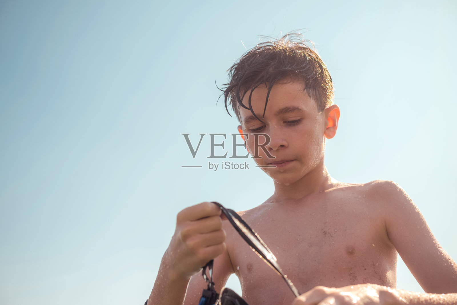 男孩潜水后摘下浮潜面罩，在太阳的背景下。旅游和夏季概念照片摄影图片