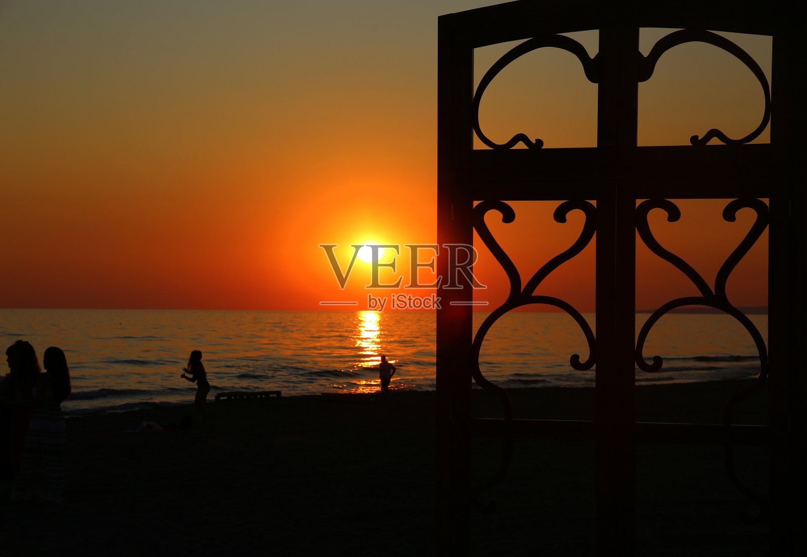 在夕阳的照耀下，海滩上的剪影照片摄影图片