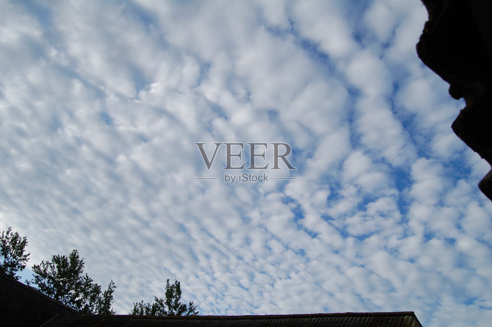 看着被屋顶环绕的清晨天空。照片摄影图片